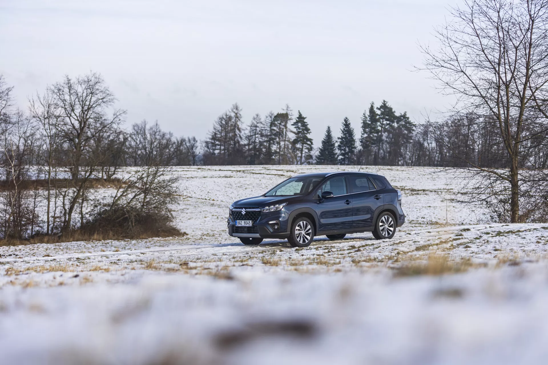 Suzuki S-Cross 2022 dans un paysage hivernal avec de la neige, mettant en avant son design dynamique, son éclairage avancé, ses jantes en alliage et ses barres de toit, soulignant son style SUV et ses capacités tout-terrain.