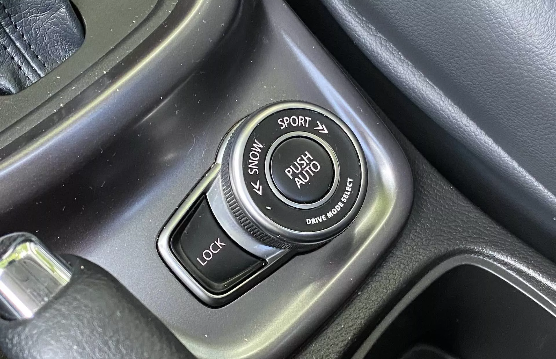 Gros plan sur le sélecteur de modes de conduite dans la console centrale d'une Suzuki Vitara 2018 avec des étiquettes pour les modes SNOW, SPORT, LOCK et AUTO, circonférence texturée et accents métalliques brossés.