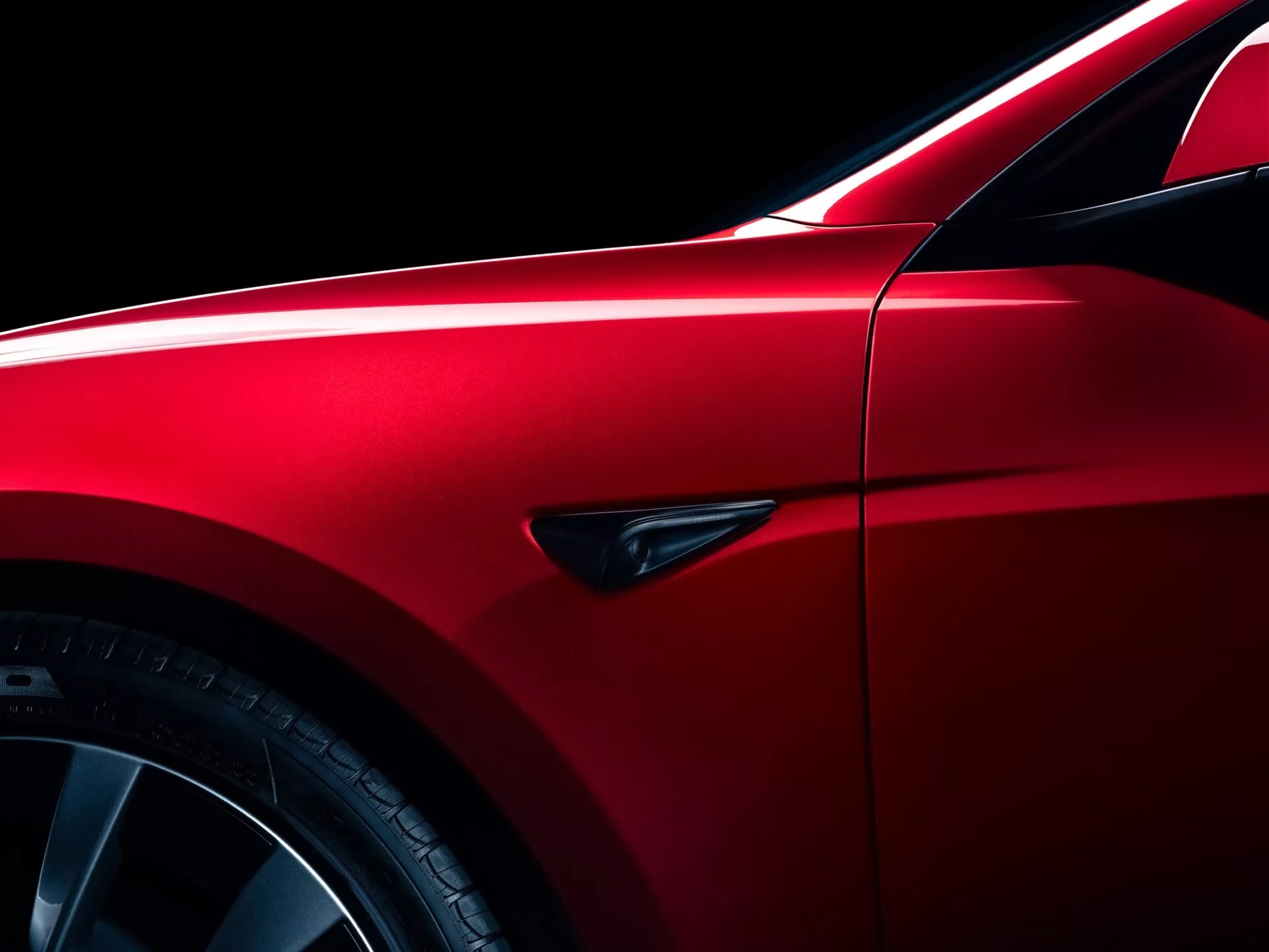 Facelift de Tesla Model-3 2023 en rouge métallisé, montrant un design aérodynamique élégant avec un focus sur l'aile, jantes en alliage multi-rayons et pneus sportifs à profil bas, soulignées par des écarts de panneau précis et un indicateur latéral distinctif.