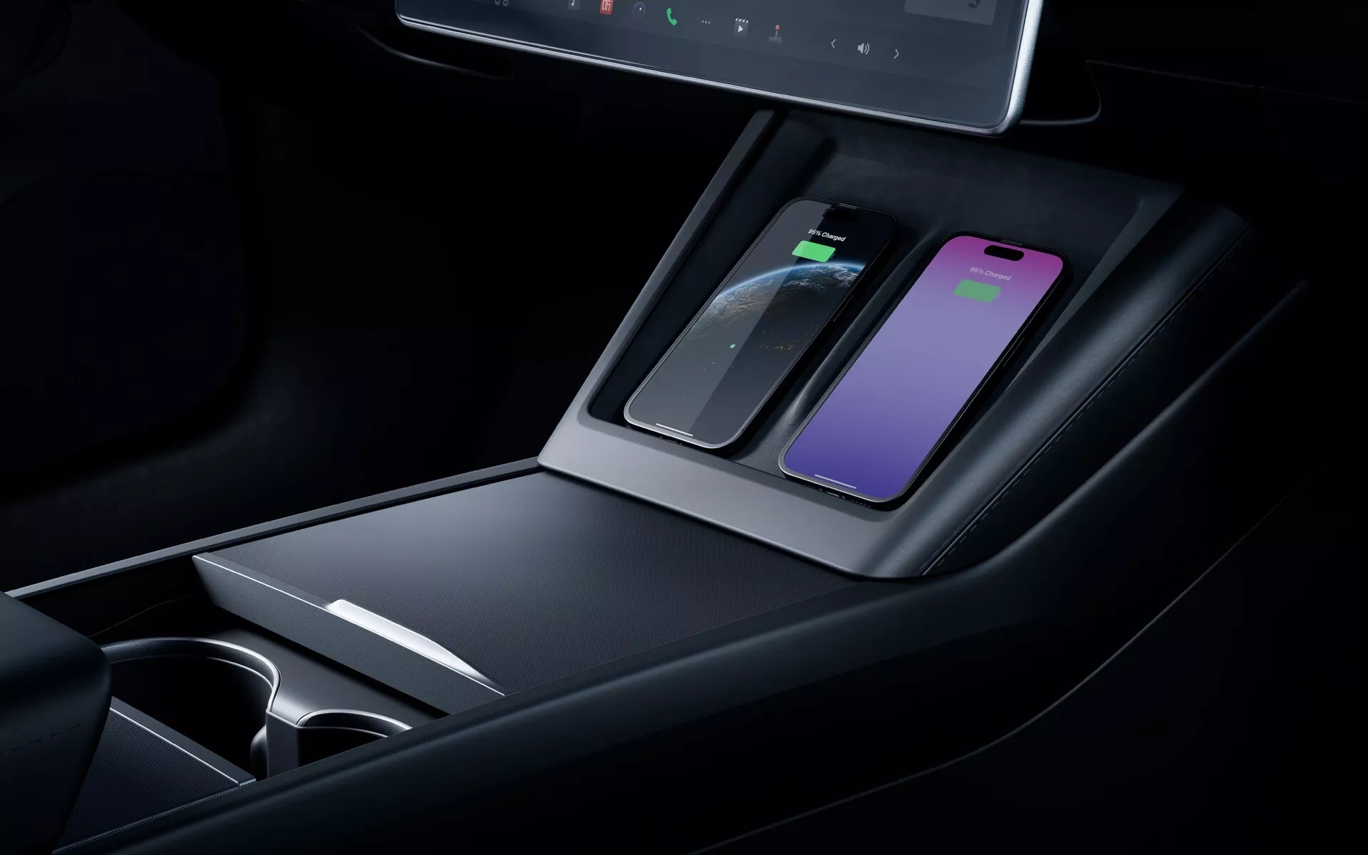 Gros plan sur la console centrale du Tesla Model 3 2023 facelift montrant le tapis de chargement sans fil, les compartiments de rangement, les porte-gobelets, les matériaux haut de gamme, l'éclairage ambiant et un affichage numérique