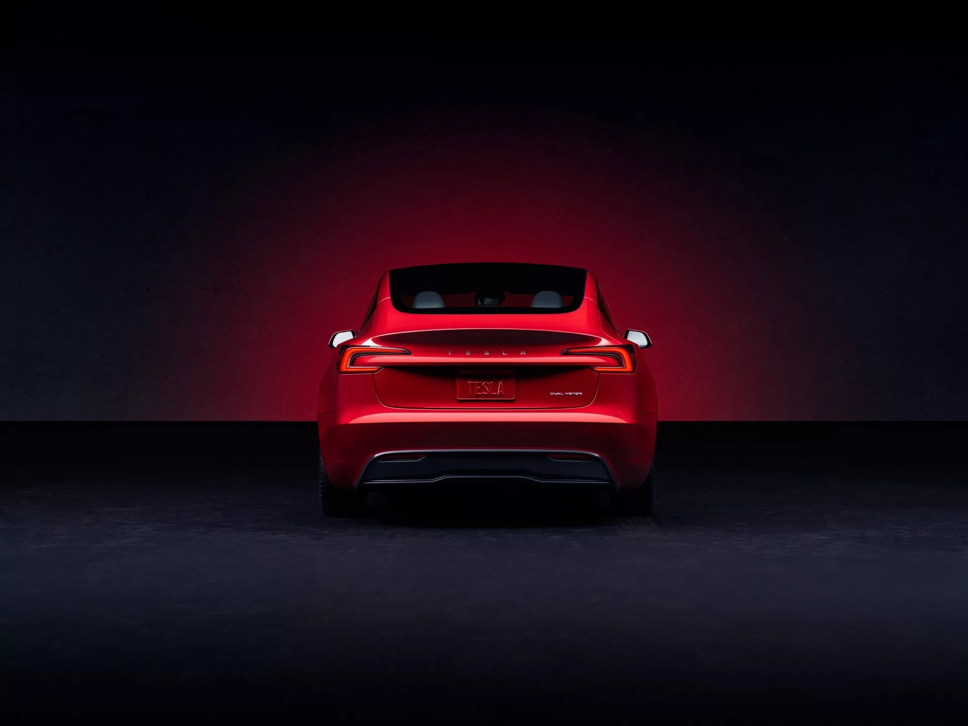 Tesla Model 3 2023 (facelift de première génération) présentée depuis une vue arrière promotionnelle dans un cadre de studio, affichant une finition rouge avec un effet halo de lumière dramatique, mettant en avant ses feux arrière LED modernes s'étendant sur la largeur, badge sans marque visible, indices de véhicule électrique sans échappement, et une silhouette sportive du pare-brise arrière.