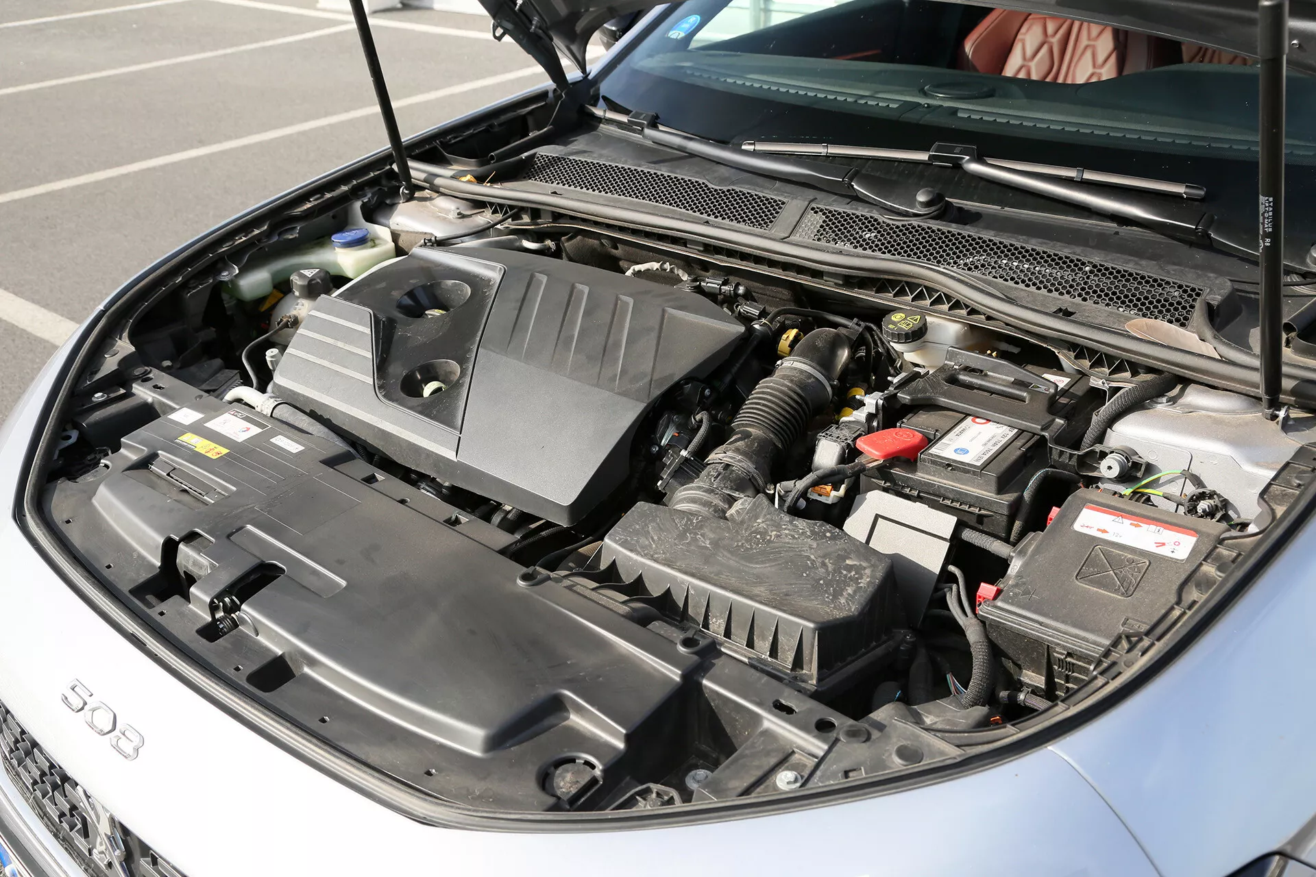 Vue de près du compartiment moteur de la Toyota Camry Limousine 2001 avec le capot ouvert, montrant la batterie, l'ensemble d'admission d'air et les réservoirs de fluide à la lumière naturelle du jour