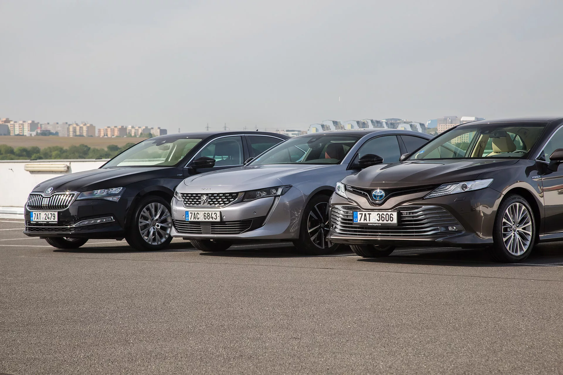 Trois limousines Toyota Camry de l'année 2001, garées côte à côte dans un parking extérieur, orientées vers la gauche avec une vue claire sur leurs grilles frontales modernes, phares et conceptions aérodynamiques