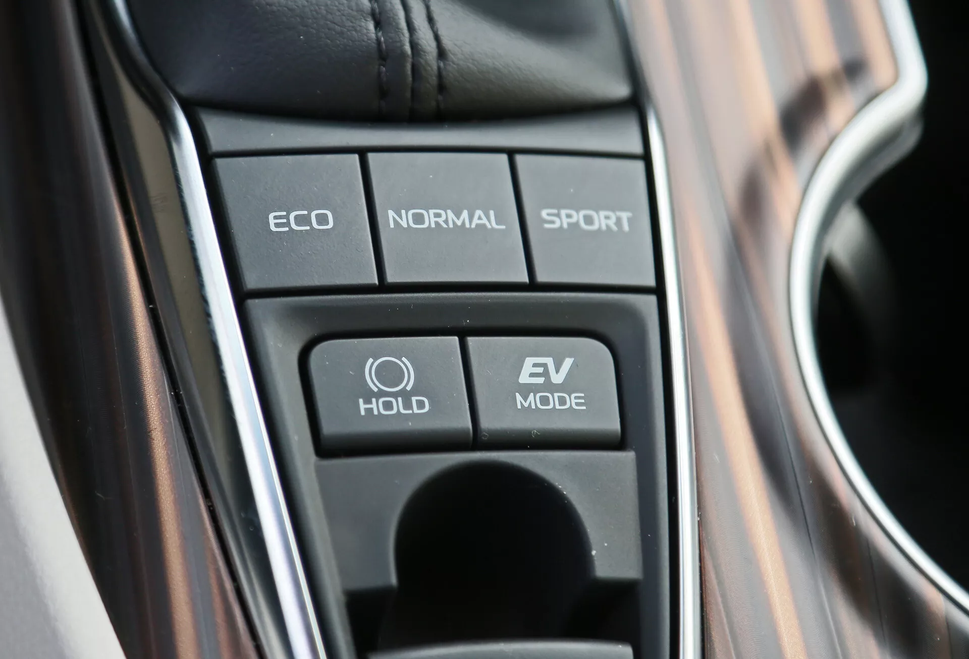 Vue rapprochée de la console centrale de la Toyota Camry 2001 montrant les boutons de sélection du mode de conduite, y compris ECO, NORMAL, SPORT, fonction HOLD et mode EV, mettant en évidence les technologies avancées du véhicule et les capacités hybrides.