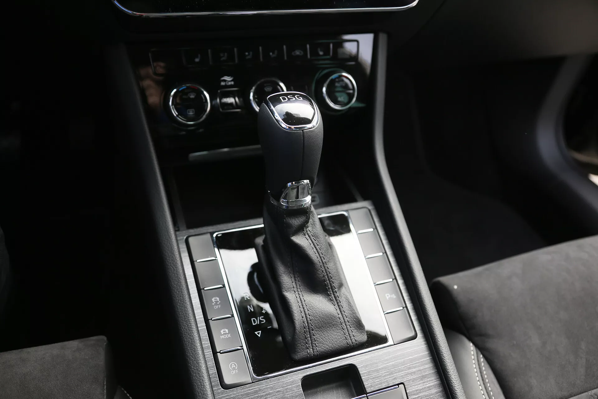 Vue intérieure d'une limousine Toyota Camry 2001 se concentrant sur la console centrale et le levier de vitesse, avec un levier enveloppé de cuir et finition chromée, entouré d'une console en métal brossé, textures de matériaux de luxe, et commandes et boutons placés stratégiquement pour la sélection des modes de conduite avancés et les réglages du véhicule