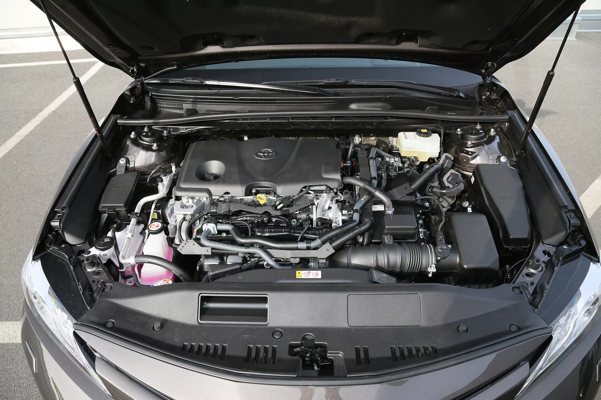 Vue détaillée du compartiment moteur ouvert d'une limousine Toyota Camry 2001, exposant un design de moteur moderne avec des composants visibles incluant le bloc moteur, le système d'admission d'air et divers connecteurs et tuyaux