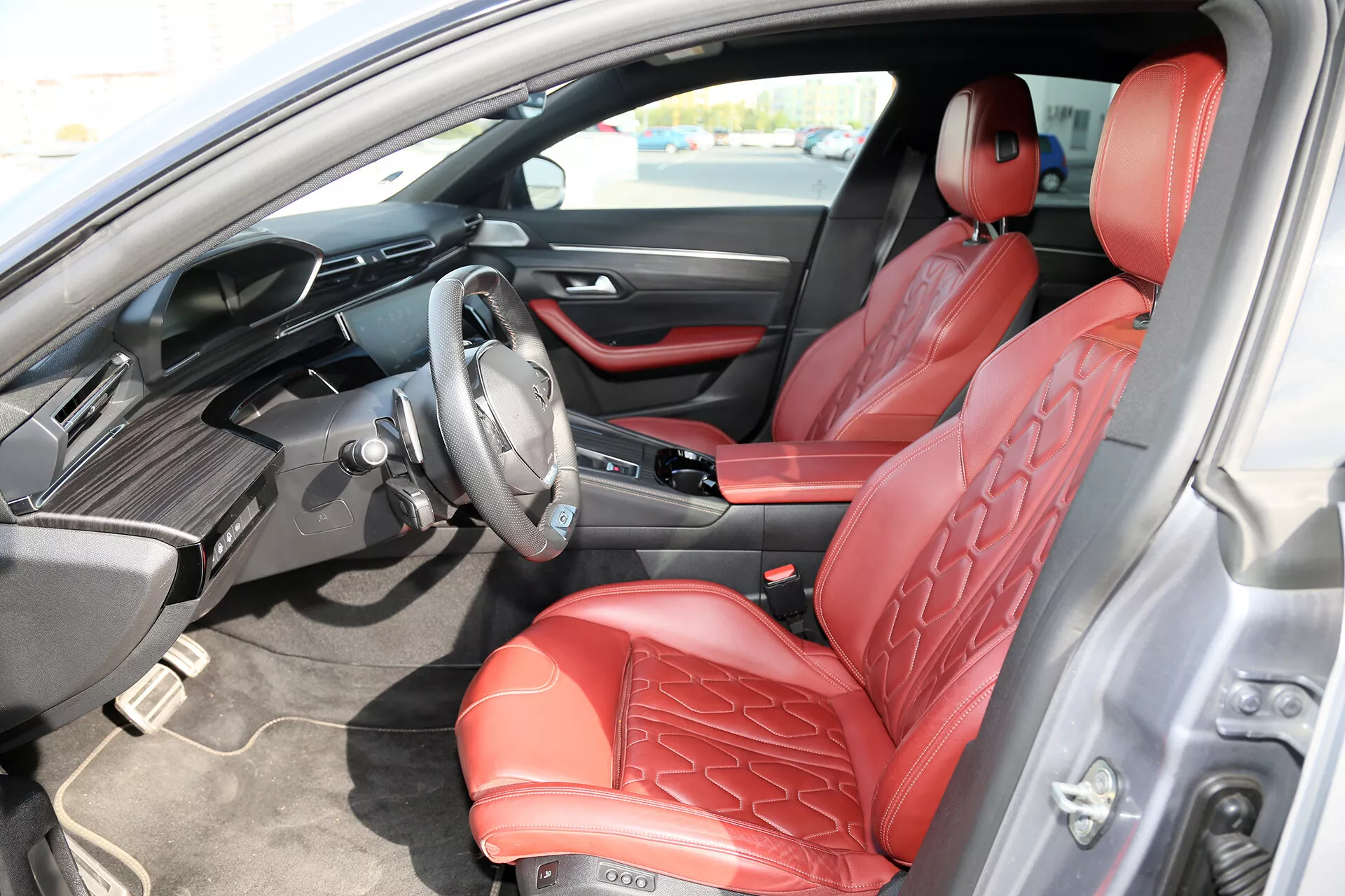 Intérieur luxueux de la limousine Toyota Camry 2001 avec sièges en cuir rouge matelassé, tableau de bord numérique avancé et volant multifonctions, système d'infodivertissement tactile et design élégant du tableau de bord vu du côté du conducteur.