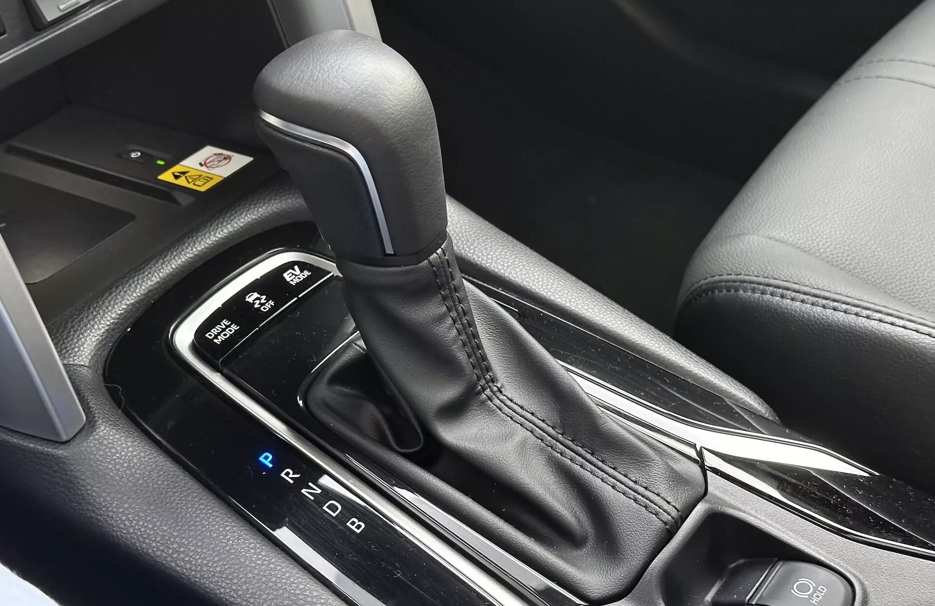 Vue intérieure détaillée de la Toyota Corolla Cross 2022 montrant le levier de vitesse automatique avec disposition PRND visible, entourée par une console centrale élégante avec des finitions en plastique noir et des accents métalliques, mettant en lumière la conception ergonomique et les caractéristiques technologiques modernes