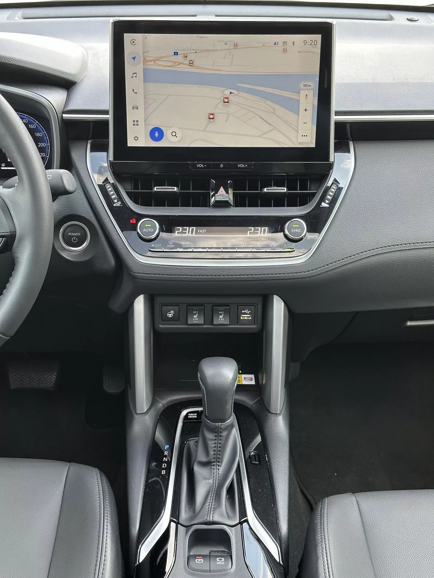 Intérieur du Toyota Corolla Cross 2022 avec système d'infodivertissement tactile avec navigation GPS, contrôle climatique bi-zone, lecteur CD, boutons de commande médias et téléphone, levier de vitesse automatique moderne et accents en cuir sur la console centrale et le design du tableau de bord