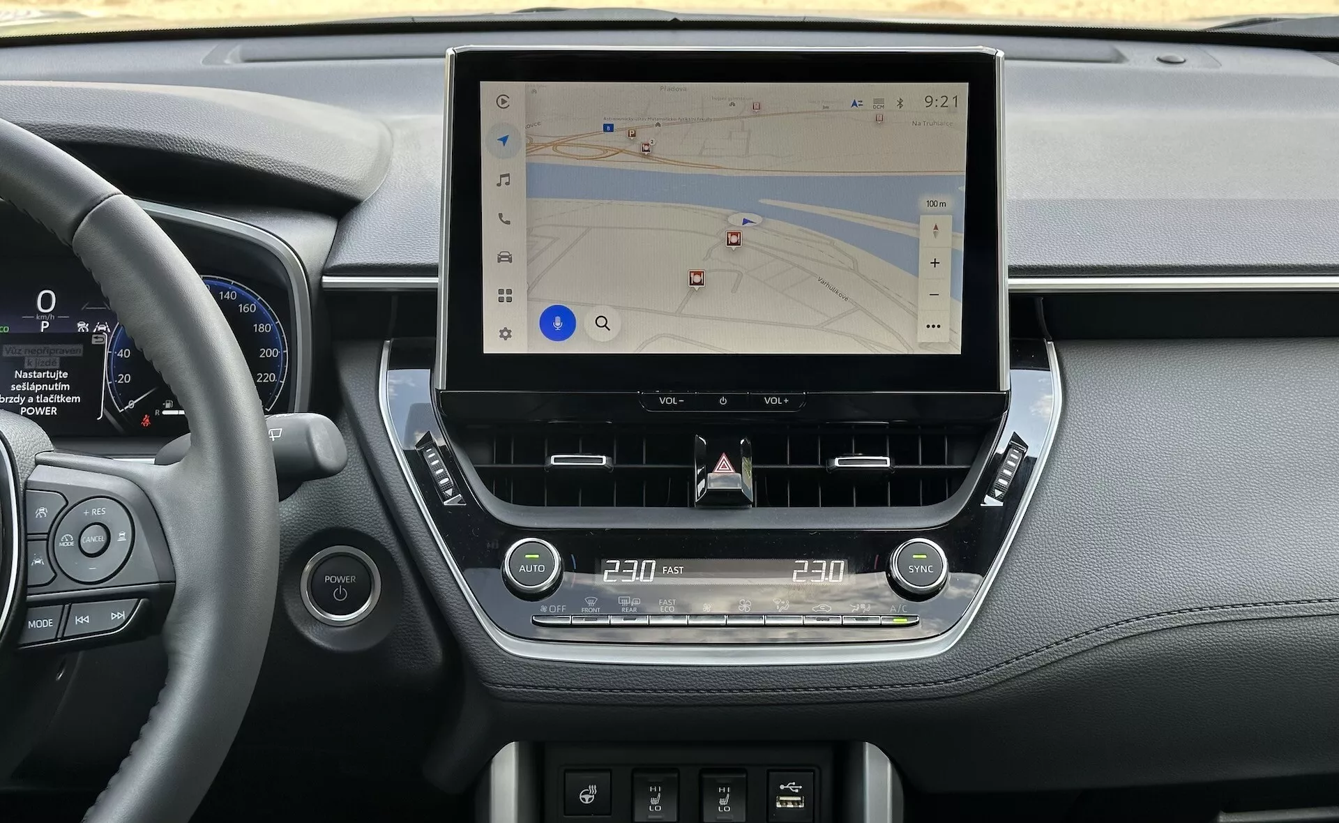 Intérieur de la Toyota Corolla Cross 2022 montrant une console centrale moderne avec un grand écran tactile vertical pour la navigation, entouré par des éléments de tableau de bord élégants incorporant des détails en cuir, un cluster d'instrumentation numérique à côté du volant, et des commandes tactiles ergonomiques pour le climat et l'audio, le tout dans une lumière naturelle.