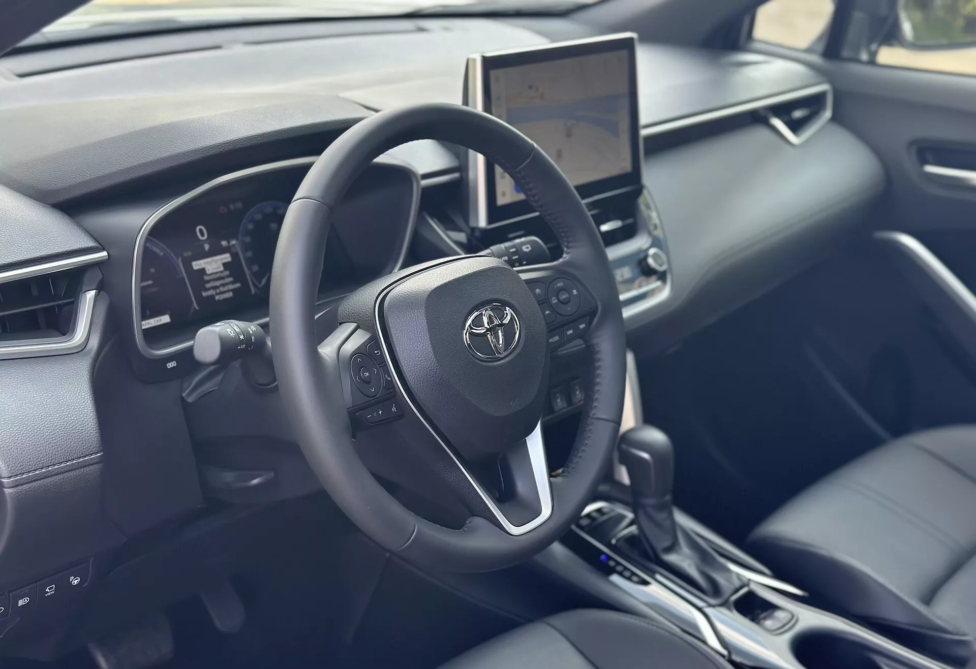 Intérieur du Toyota Corolla Cross 2022 se concentrant sur le côté conducteur avec volant détaillé, tableau de bord numérique et écran tactile d'infotainment central offrant des technologies modernes et des accents en cuir noir