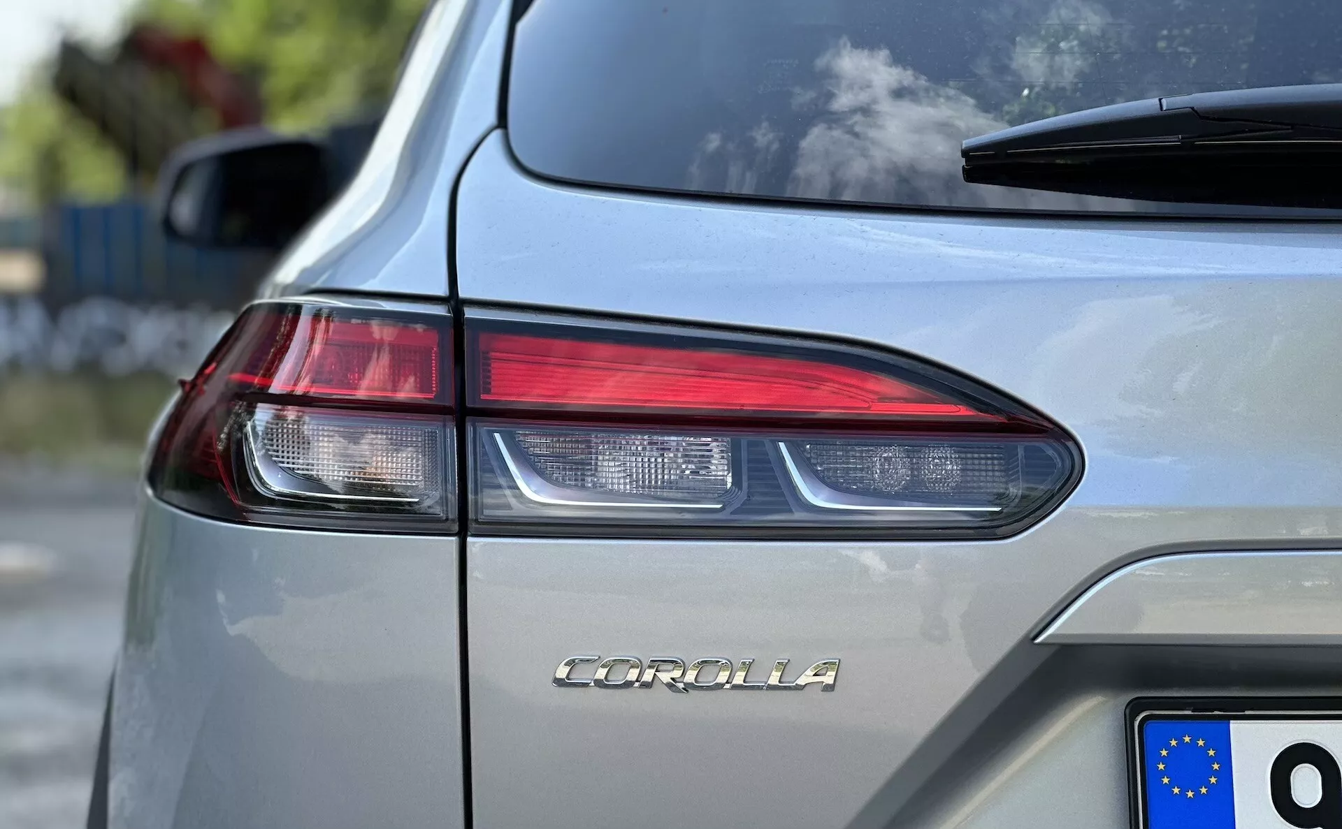 Image en gros plan d'une Toyota Corolla Cross 2022 montrant le nom du modèle sur le coffre, mettant en évidence la conception des feux arrière LED angulaires et la plaque d'immatriculation de l'Union Européenne sur une carrosserie métallisée argent