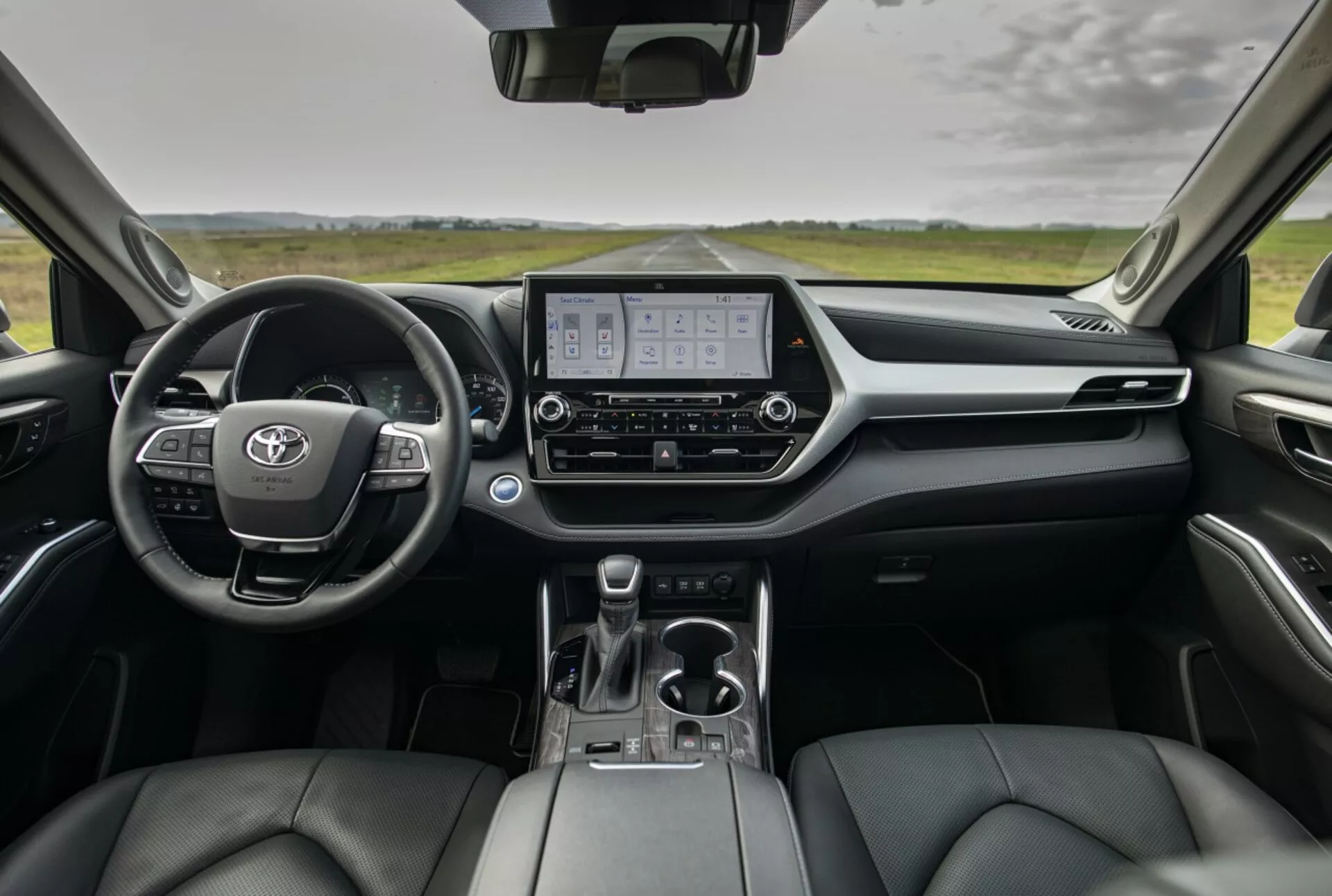 Vue d'ensemble de l'intérieur du Toyota Highlander 2021 montrant le tableau de bord, le cluster d'instruments numérique, l'affichage du système d'infodivertissement et les sièges avant en cuir depuis la perspective des sièges arrière