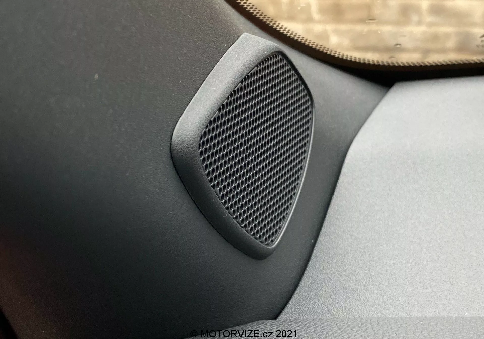 Gros plan d'un haut-parleur de voiture sur le panneau de porte avec un motif de grille géométrique, intégré en gris foncé ou noir dans le panneau, pris d'un angle élevé mettant en évidence la texture du haut-parleur et la qualité audio dans une Toyota Yaris 2020.