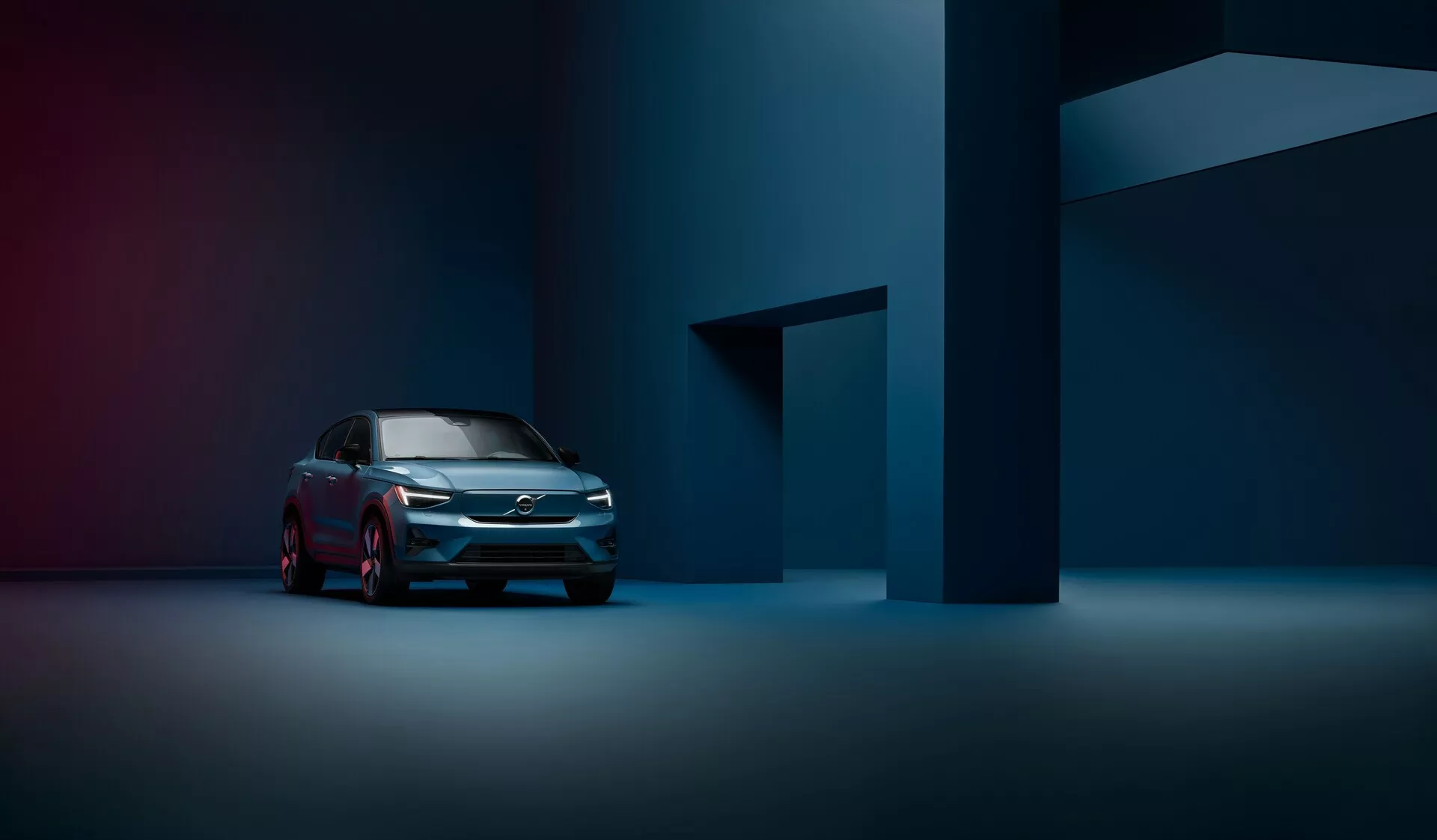 Une photographie professionnelle d'une Volvo C40 2021 (1ère génération) vue de trois quarts avant, mettant en valeur la calandre moderne, les phares LED et le profil latéral élégant dans un studio faiblement éclairé et atmosphérique.