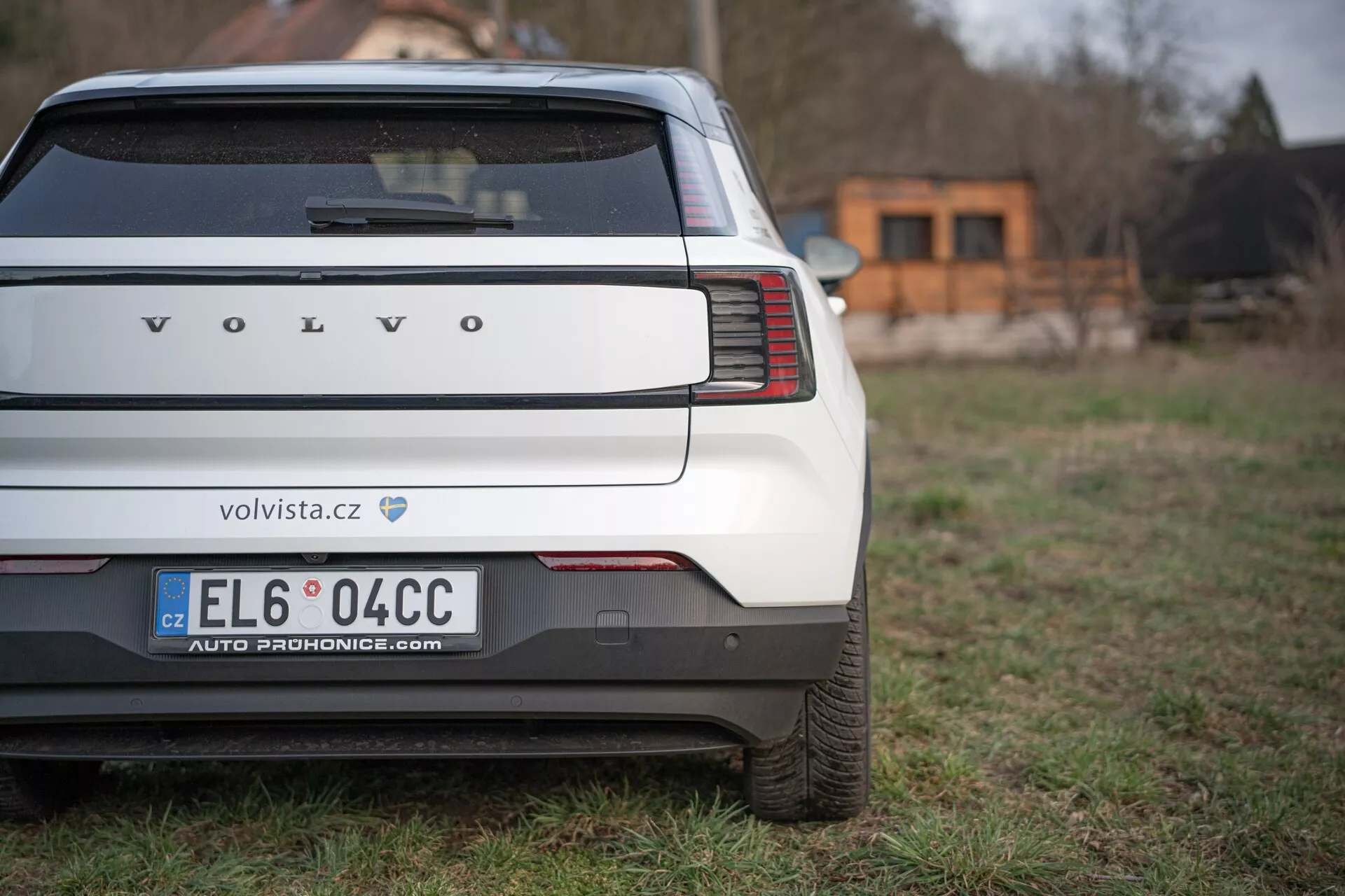 Vue arrière d'une Volvo EX30 2024 mettant en évidence les feux arrière verticaux uniques, le pare-chocs arrière et la zone de la plaque d'immatriculation sur un fond herbeux