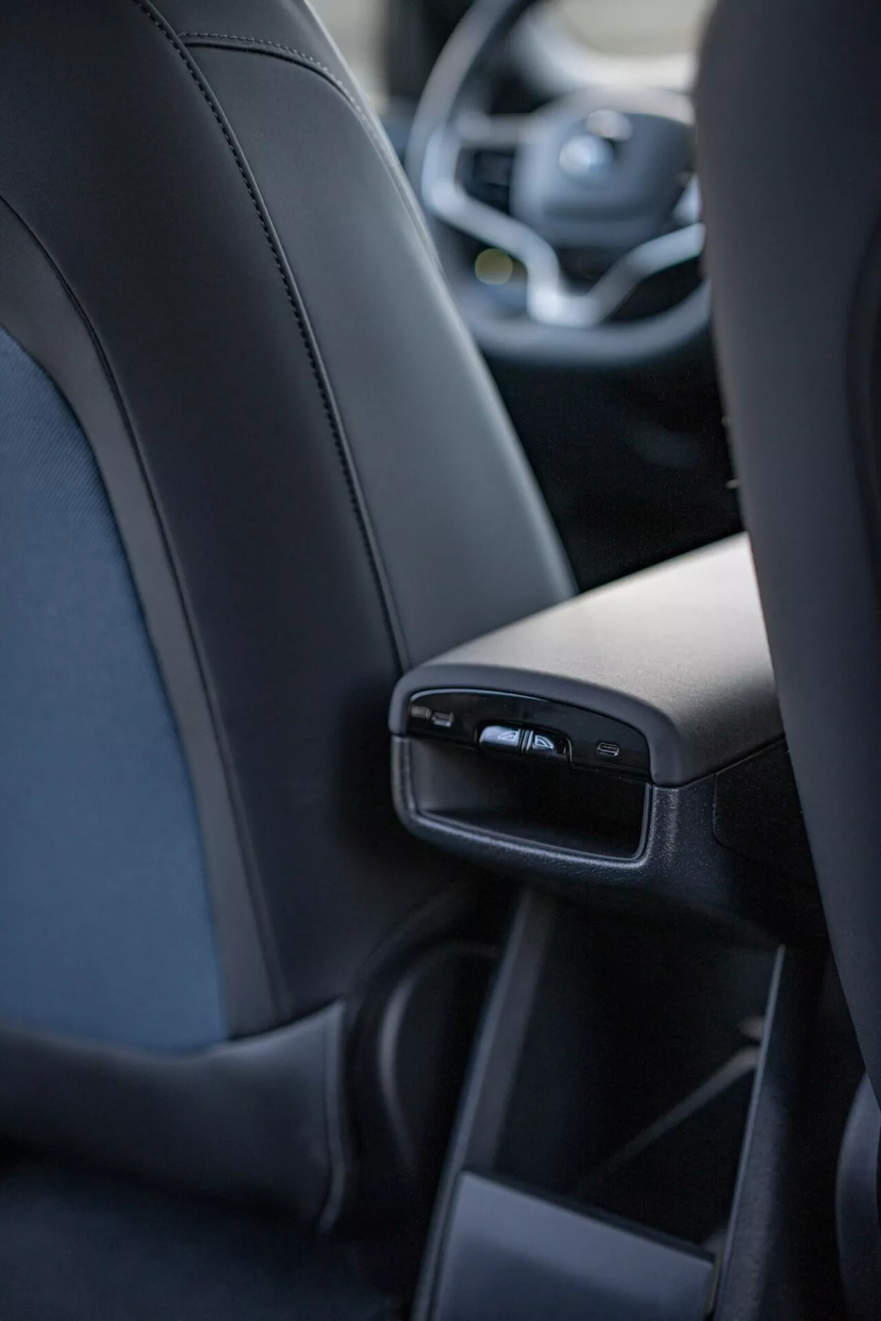 Vue intérieure du Volvo EX30 2024 mettant en avant les détails de la console centrale arrière du point de vue du passager arrière central, incluant des ports USB et des bouches d'air, soulignant le luxe et la technologie