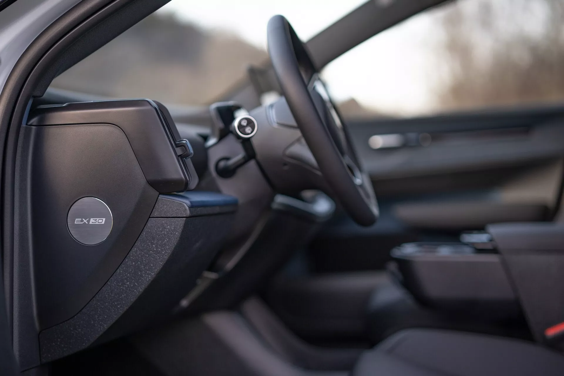 Vue intérieure de la Volvo EX30 2024 se concentrant sur le côté conducteur avec un design de siège sportif ou premium détaillé, système audio Harman Kardon sur le montant B, volant multifonction et aperçus d'un système d'infodivertissement avancé et de la conception du panneau de porte du passager