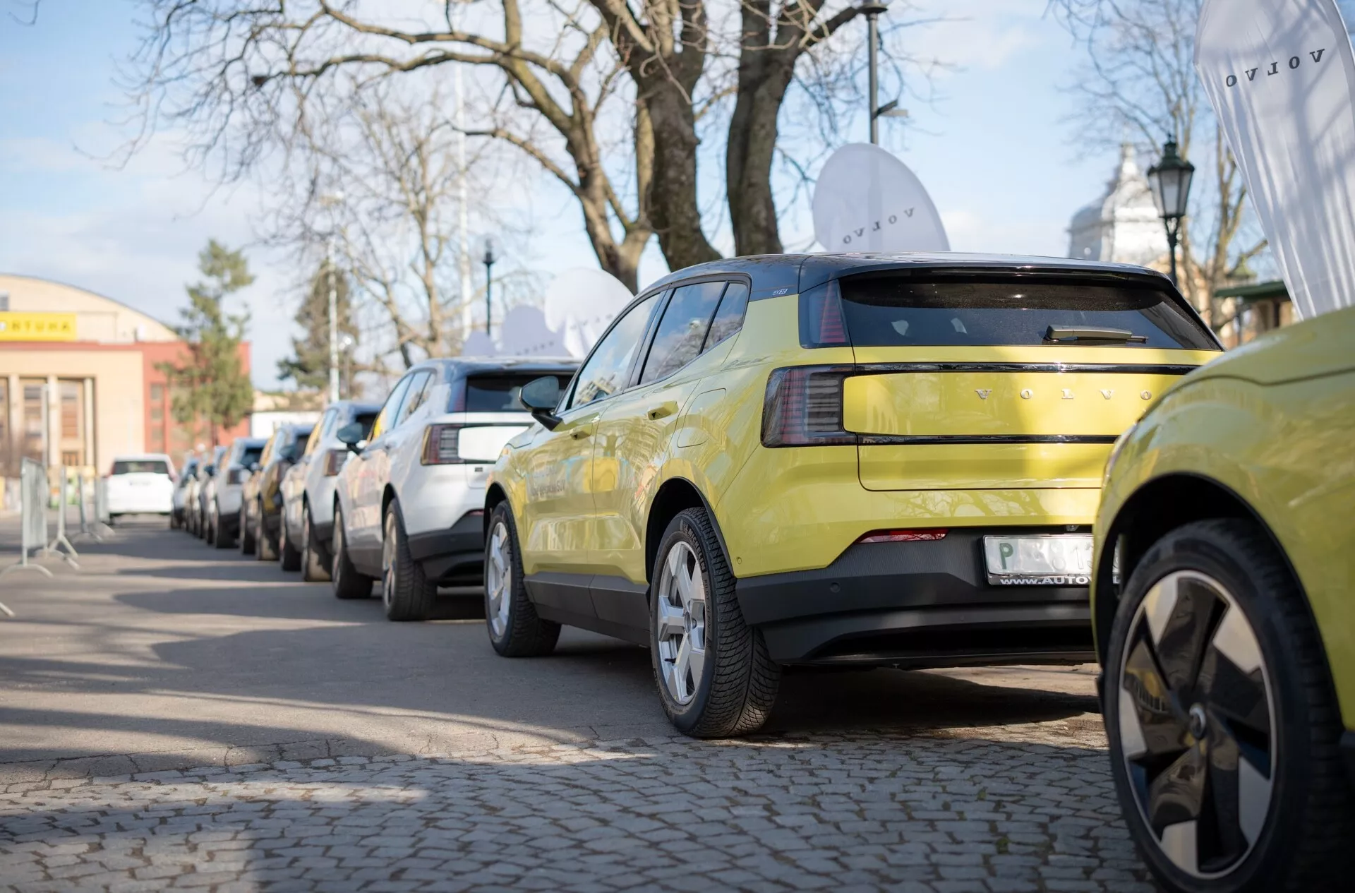 Volvo EX30 de 2024 en vert lime, montrant sa vue arrière avec un ensemble de lumières arrière LED et des jantes en alliage à plusieurs branches, garée le long d'une rue urbaine