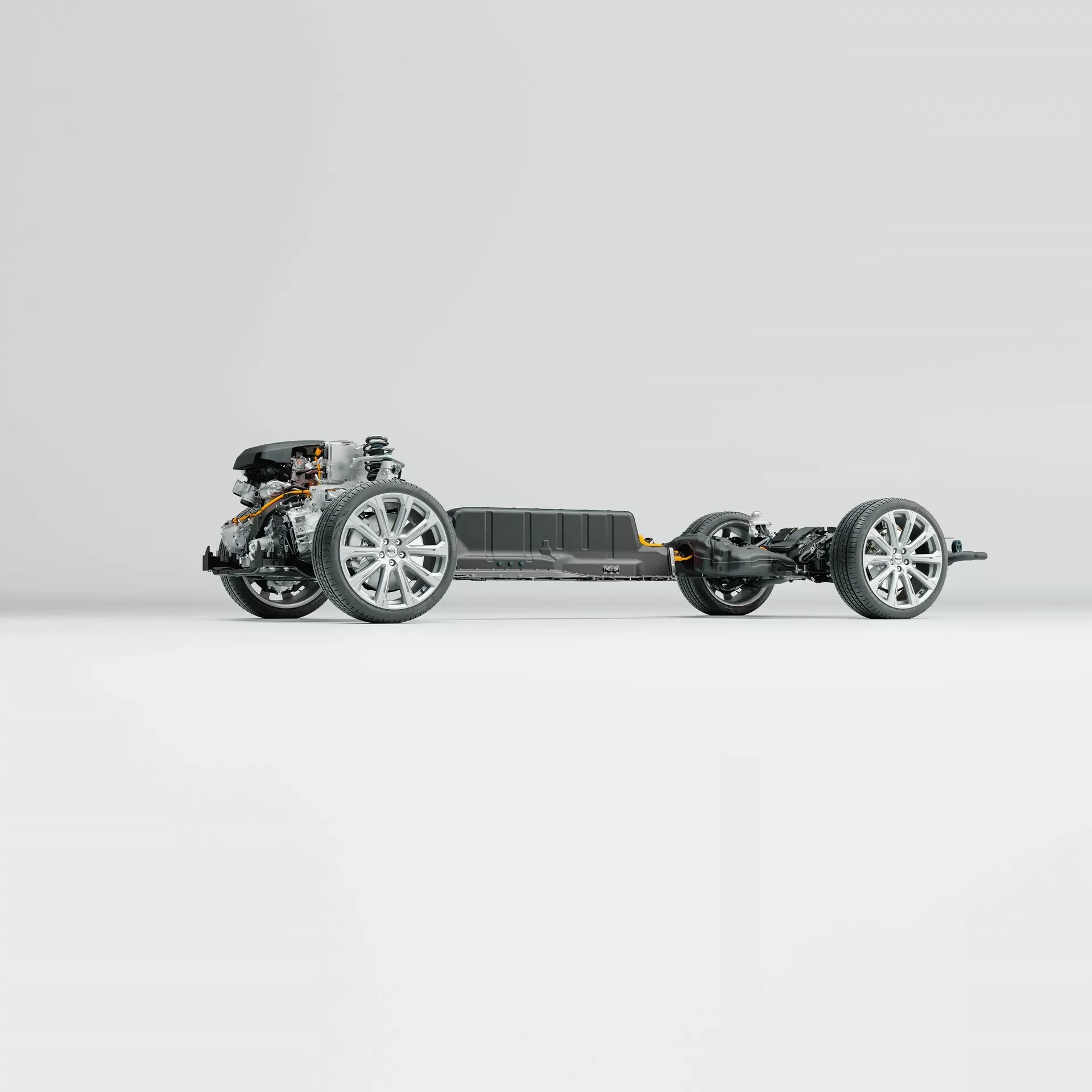 Vue de profil du châssis roulant du Volvo XC60 2021 (deuxième génération-restylage). L'image met en valeur le cadre du véhicule, les roues équipées de jantes en alliage modernes, les composants de la suspension, la transmission avant et un pack batterie central, le tout monté sur un fond propre et neutre. La photo révèle des détails complexes de l'ingénierie avancée sans la carrosserie ni les composants intérieurs.