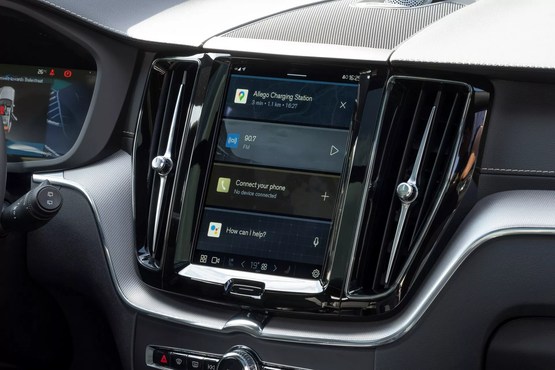 Vue intérieure d'un Volvo XC60 2021 (deuxième génération, lifting) se concentrant sur le système d'infodivertissement central. L'écran orienté verticalement, similaire aux tablettes et aux smartphones, est encadré par des bouches d'aération métalliques suggérant un modèle haut de gamme. Sous l'écran, des boutons physiques et une molette suggèrent une combinaison de commandes tactiles et physiques. L'écran de navigation indique une fonctionnalité GPS, avec des invites pour la connectivité du téléphone et le contrôle vocal, suggérant des fonctionnalités comme le Bluetooth, la reconnaissance vocale et l'intégration du smartphone. L'heure est affichée à 09h07. L'image met en évidence les fonctionnalités du système d'infodivertissement sans montrer de marquages ou d'identifiants de modèle.