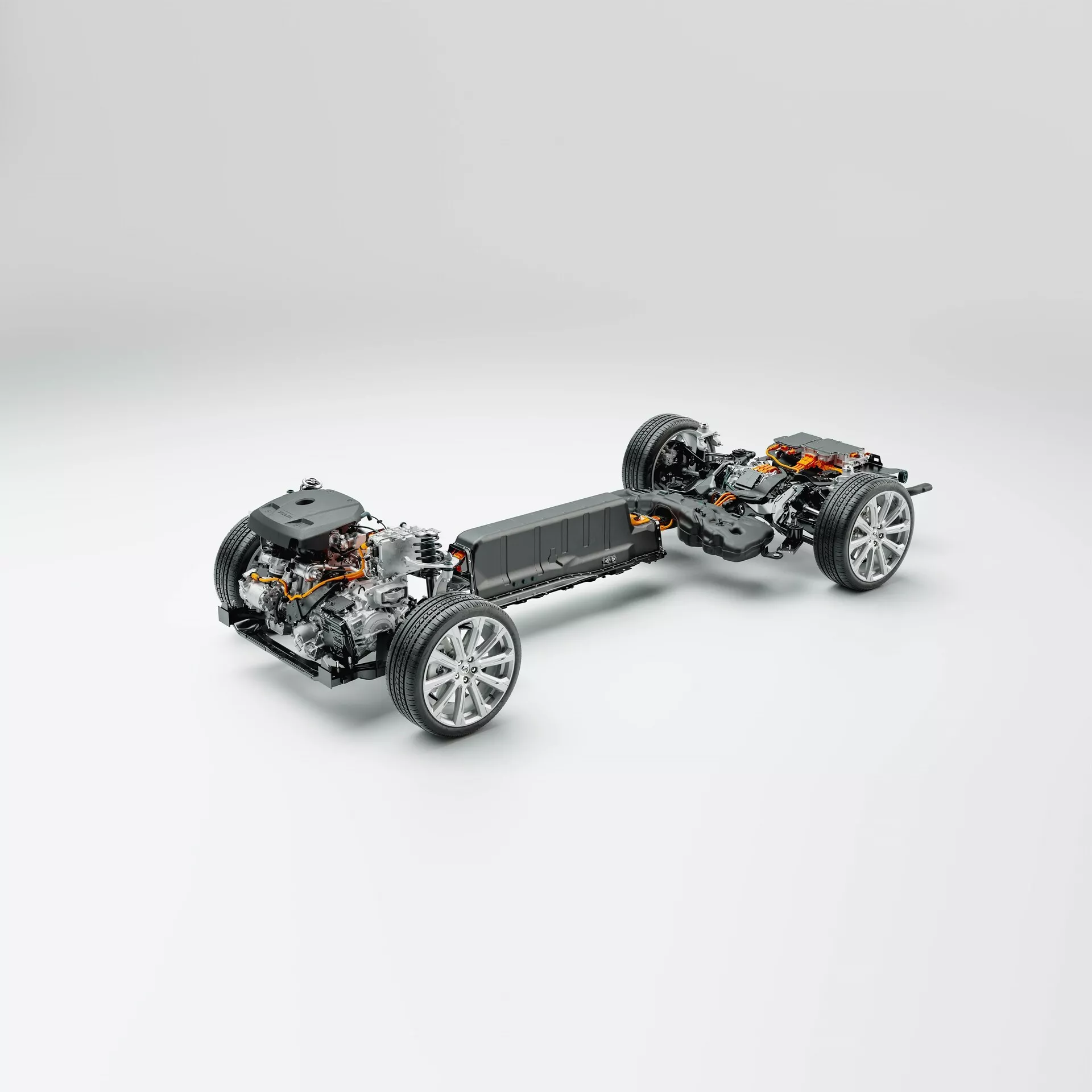 Vue de trois quarts en plongée de la plateforme du Volvo XC60 2021 (2e génération restylée) sans panneaux de carrosserie extérieurs, mettant en avant le châssis, la transmission et les composants de suspension. Le véhicule est centré sur un fond gris clair neutre. L'avant de la voiture est en bas, légèrement tourné vers la gauche, montrant une vue claire des roues avant et de la suspension. Vue détaillée du mécanisme de direction, de l'assemblage de la roue avec des jantes en alliage sport et des composants de freinage. La section centrale révèle le pack de batteries indiquant une plateforme de véhicule électrique (EV), intégrée au plancher pour un centre de gravité plus bas. Le moteur électrique et la chaîne de traction sont visibles derrière la batterie, suggérant une transmission arrière ou intégrale. Les roues arrière présentent une suspension et des composants de frein similaires. Idéal pour les catégories telles que la technologie automobile, les véhicules électriques, l'ingénierie mécanique et la conception de véhicules.