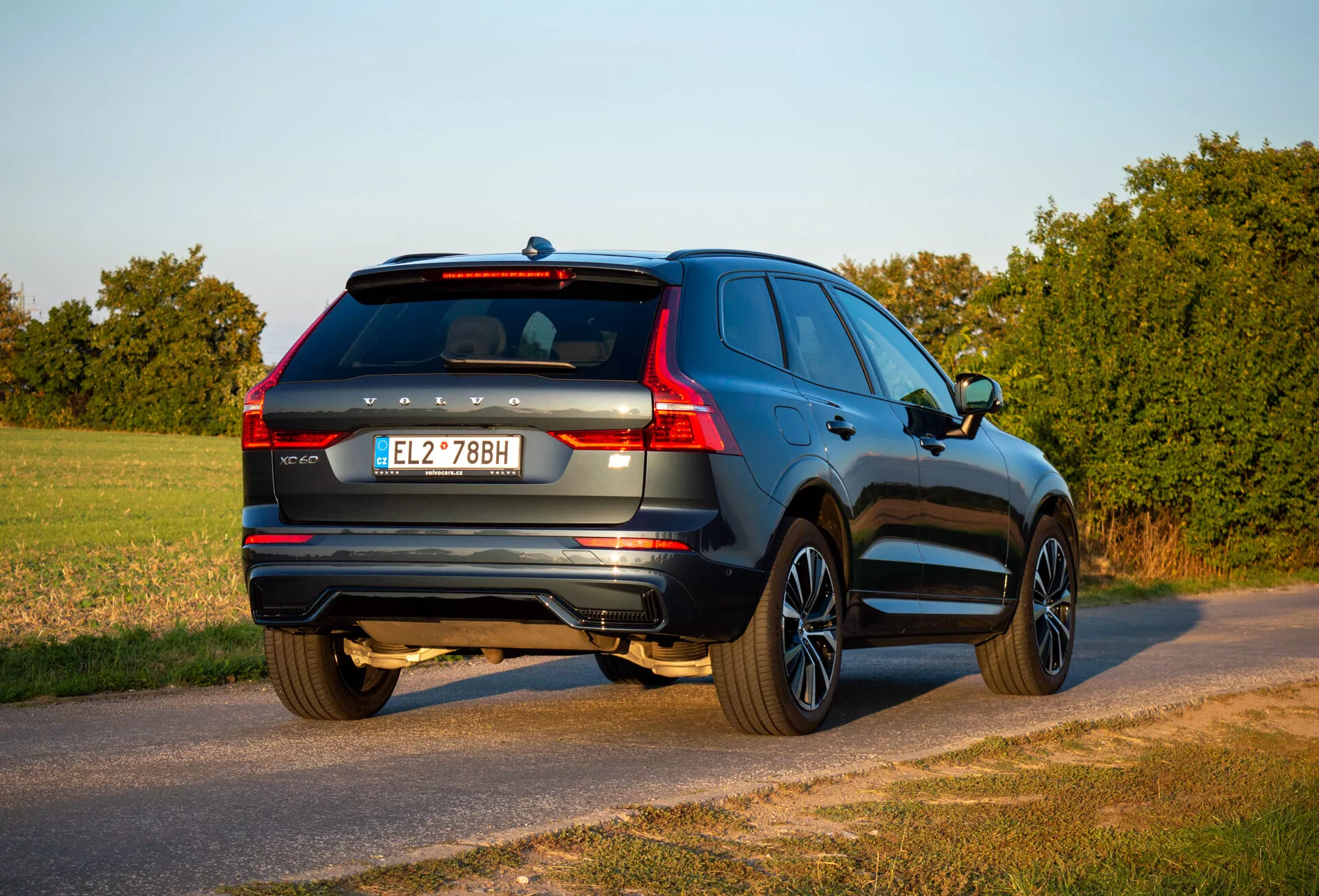 SUV Volvo XC60 Recharge hybride rechargeable 2021 vu de trois quarts arrière stationné sur une route de campagne pendant l'heure dorée avec l'arrière, le côté passager, les détails du hayon et les caractéristiques de conception visibles