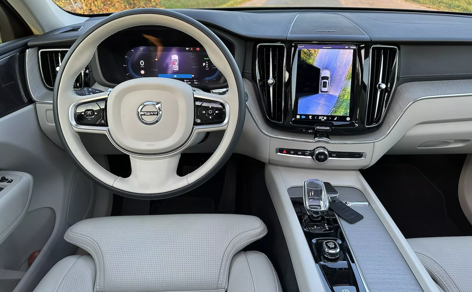 Vue intérieure du Volvo XC60 Recharge Plug-in Hybrid 2021 depuis le siège arrière, montrant le tableau de bord, les affichages numériques, le volant multifonction et la console centrale