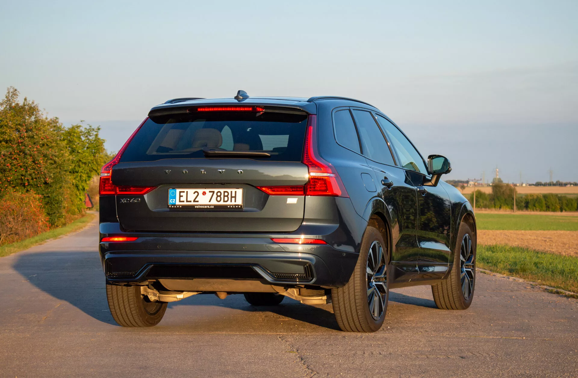 SUV Volvo XC60 Recharge hybride branchable de 2021 stationné sur une route pavée montrant sa vue arrière trois quarts, mettant en lumière les feux arrière LED, les roues en alliage et le design dynamique dans un cadre rural sous un ciel dégagé