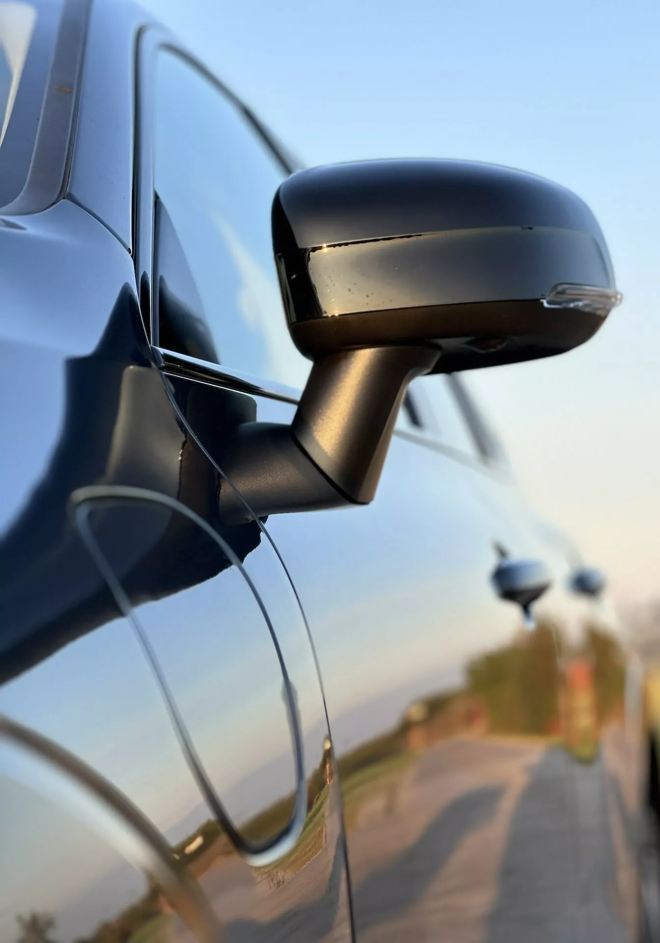 Vue rapprochée du rétroviseur latéral de la Volvo XC60 Recharge Plug-In Hybrid 2021 montrant son design élégant, son clignotant intégré, et son attachement à la portière de la voiture, soulignant la technologie automobile et les caractéristiques de sécurité.