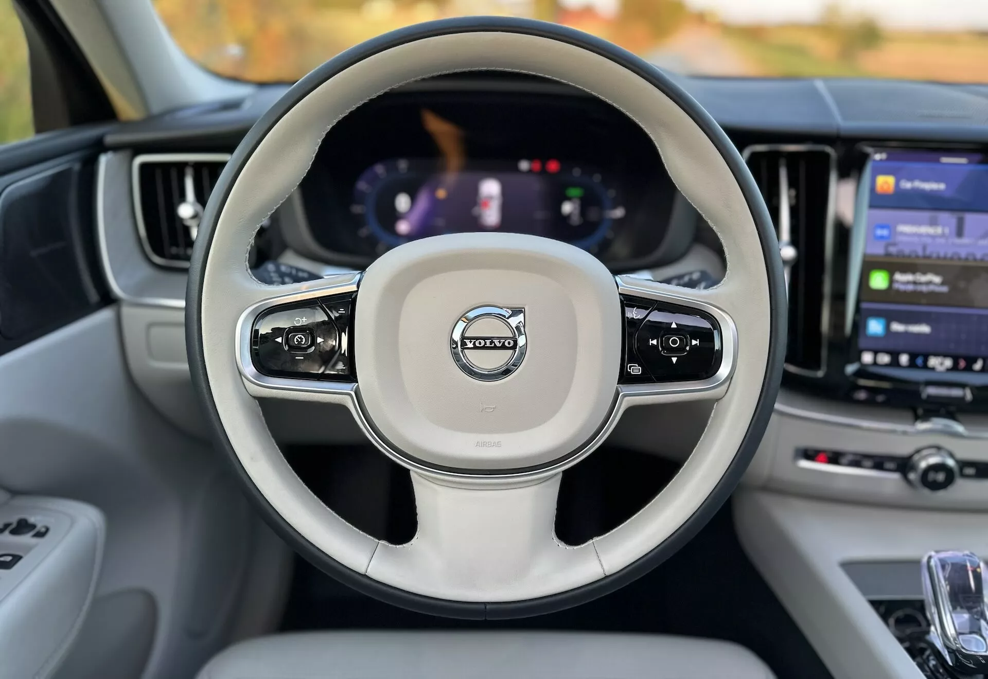 Vue intérieure d'une Volvo XC60 Recharge Plug-In Hybrid 2021 depuis le siège conducteur montrant le volant avec commandes intégrées, un tableau de bord numérique et un grand système d'infodivertissement tactile