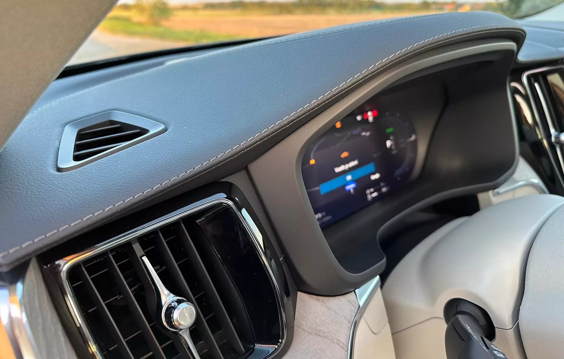 Vue intérieure d'une Volvo XC60 Recharge Plug-In Hybrid 2021, mettant en évidence le tableau de bord avec un focus sur le cluster d'instruments numériques avancé et les matériaux de haute qualité, du point de vue du siège passager avant.