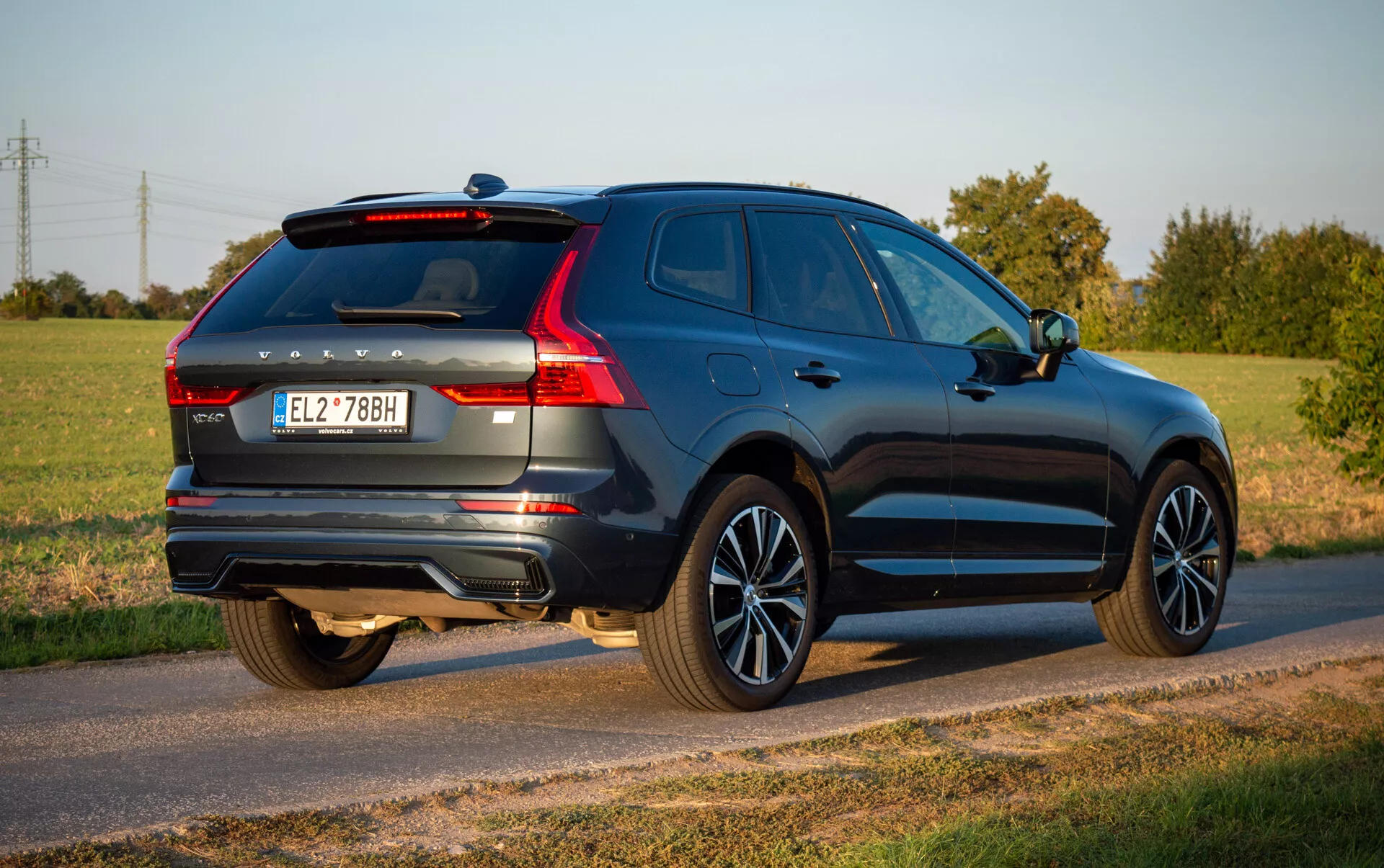 Volvo XC60 Recharge Plug-In Hybrid 2021 en bleu profond, mettant en avant son design aérodynamique et caractéristiques modernes comme feux arrière LED, roues en alliage et système d'échappement double, garée sur une route de campagne sous un ciel dégagé