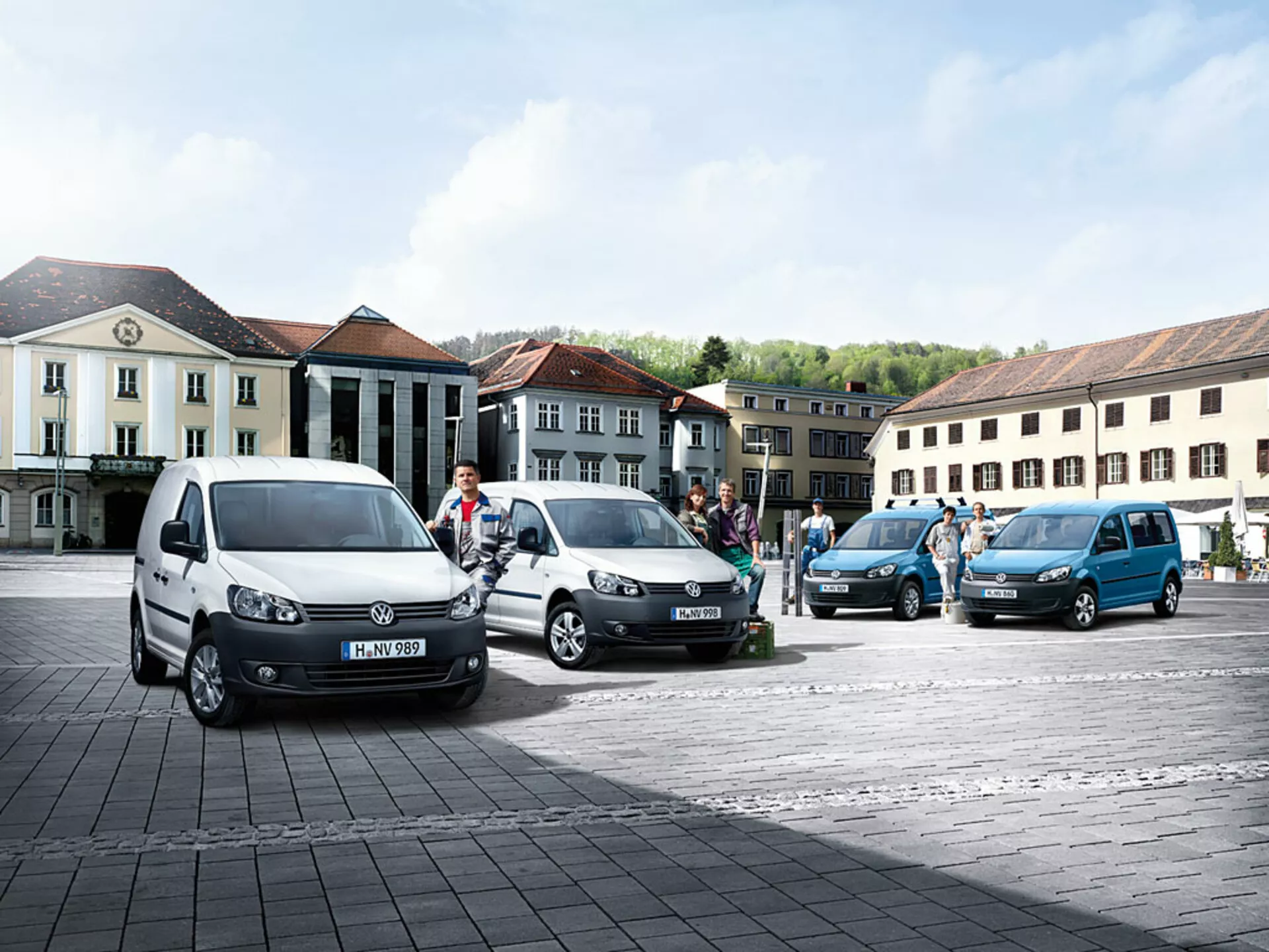 Fourgons polyvalents Volkswagen Caddy 2010 garés en ligne diagonale sur une place pavée, présentant différentes couleurs et angles, avec des profils avant et latéraux distinctifs visibles