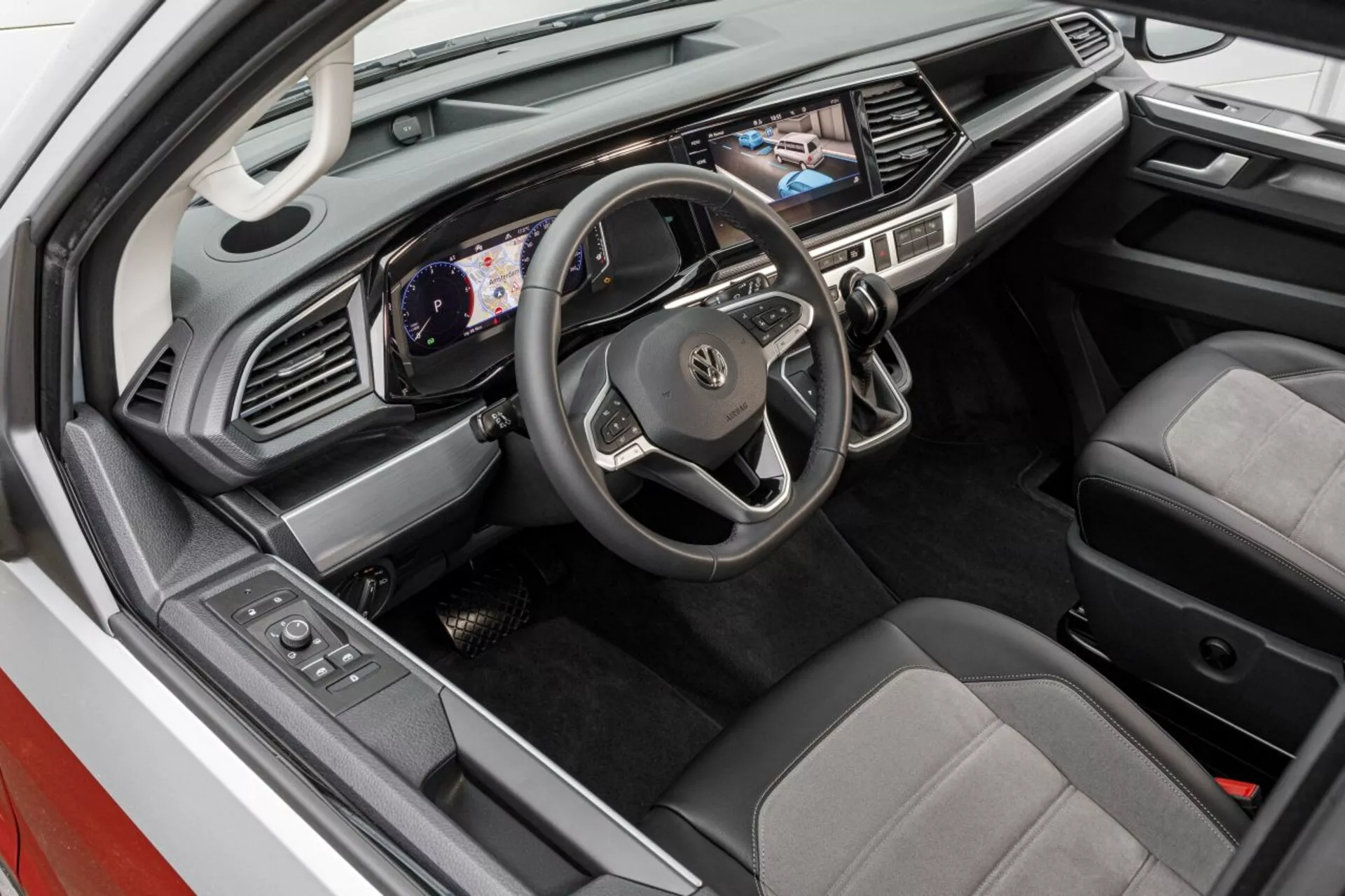 Vue en hauteur de l'intérieur du Volkswagen Nutzfahrzeuge Transporter 2019 (T6.1 California) présentant la zone du conducteur avec tableau de bord numérique, écran tactile multimédia et sièges bicolores