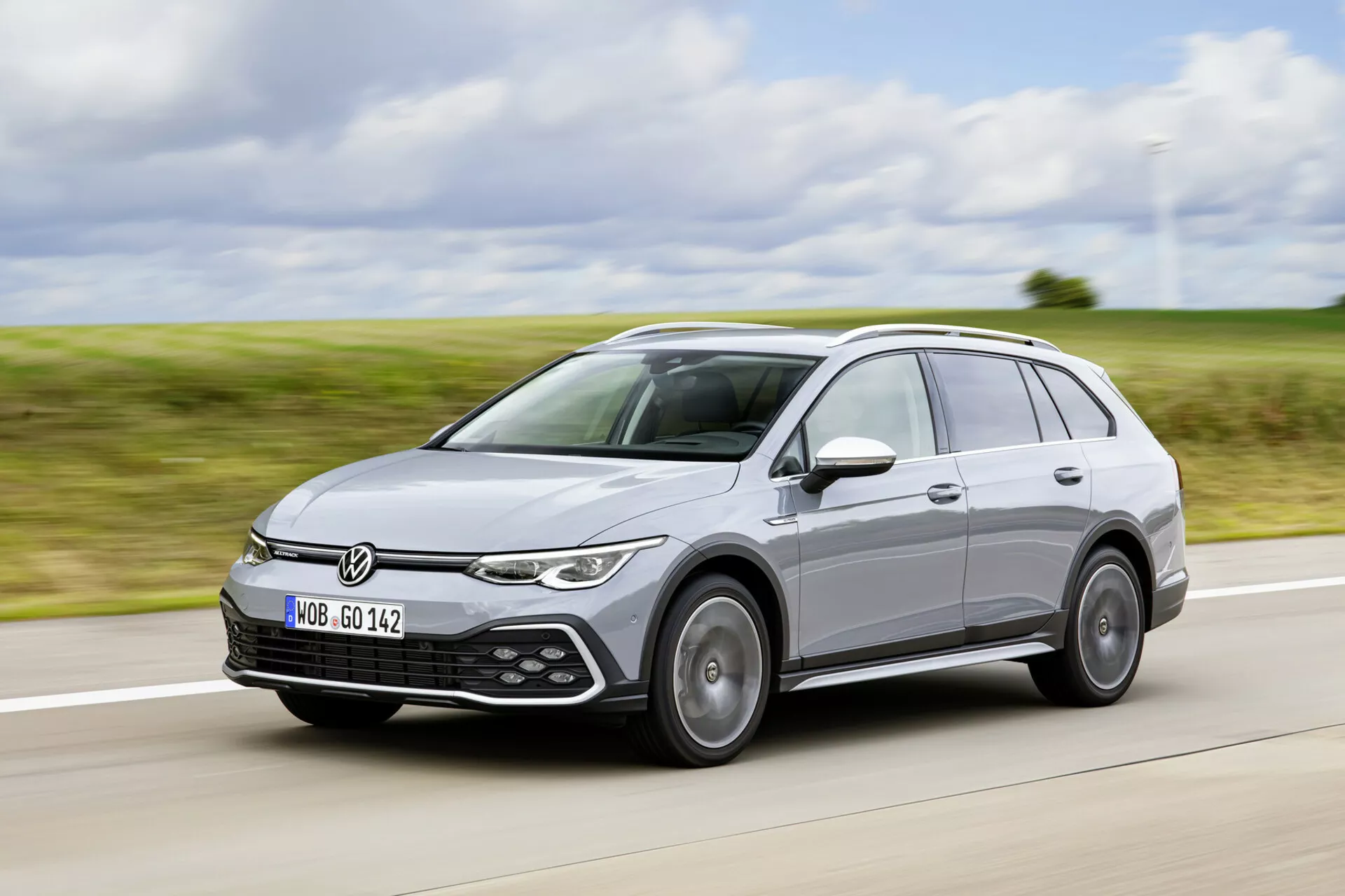 Volkswagen Golf Alltrack 2017 en mouvement sur une autoroute, montrant son design moderne de break, phares LED, capteurs d'assistance au stationnement et système de barres de toit depuis un angle avant de trois quarts.