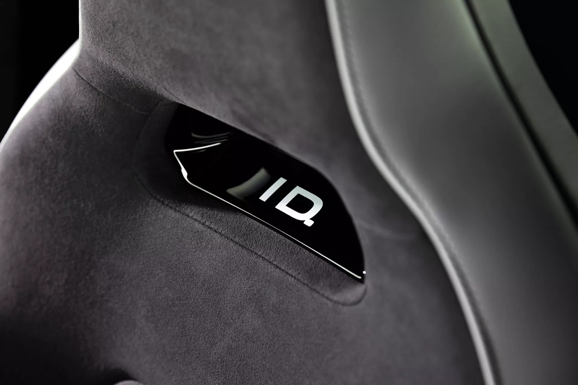 Vue rapprochée du logo 'ID' rétroéclairé sur tissu de haute qualité d'un siège de voiture dans un VW ID.3 2023 (1ère génération restylée), mettant en avant un design intérieur moderne et une technologie avancée