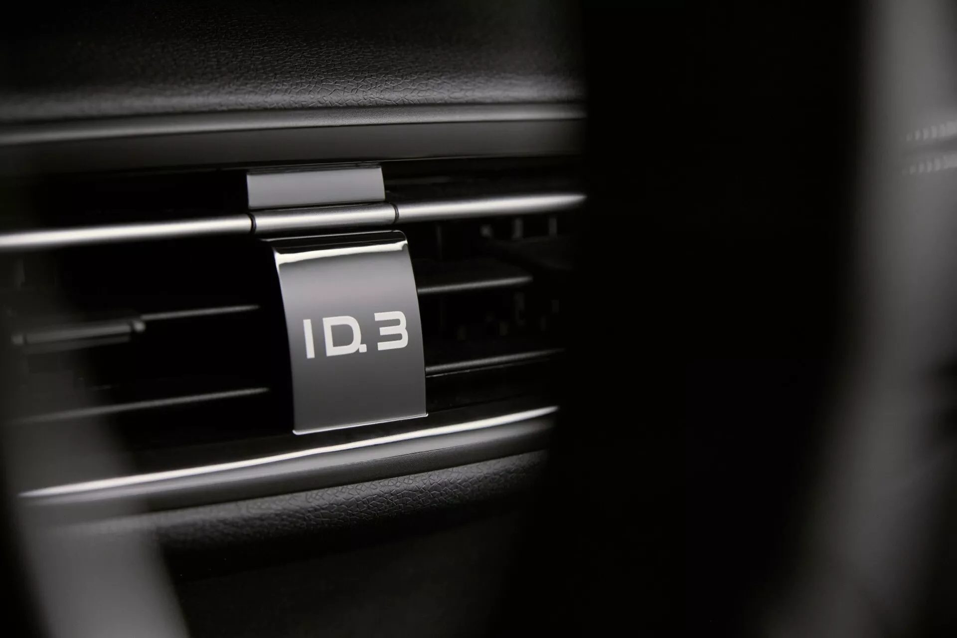 Gros plan sur l'intérieur de la Volkswagen ID.3 2023 se concentrant sur la ventilation et la plaque du modèle, mettant en lumière l'identité électrique de la voiture avec une faible profondeur de champ