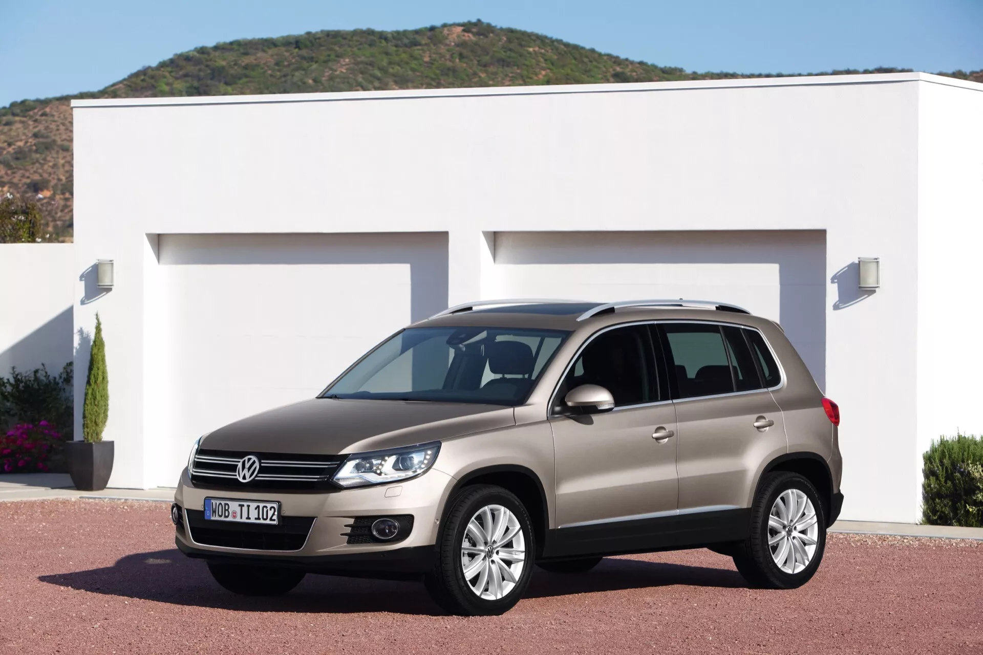 Volkswagen Tiguan de 2007 garée sur une allée devant une maison moderne, mettant en avant ses roues en alliage, phares distinctifs, feux diurnes et barres de toit, dans un cadre éclairé par une lumière diurne