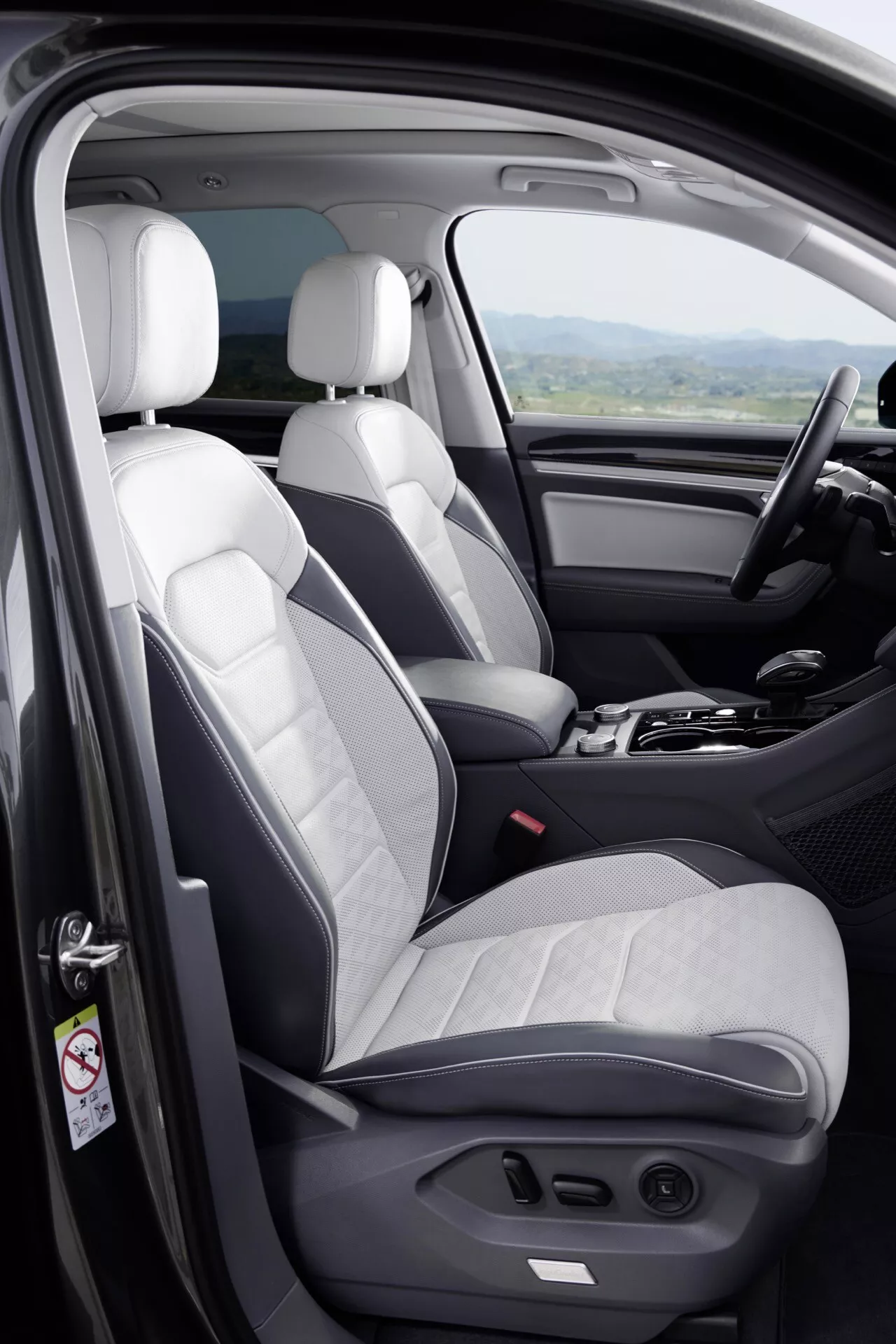 Intérieur du Volkswagen Touareg III facelift 2023 montrant des sièges avant bicolores, porte côté conducteur avec commandes et bord du tableau de bord depuis un angle surélevé
