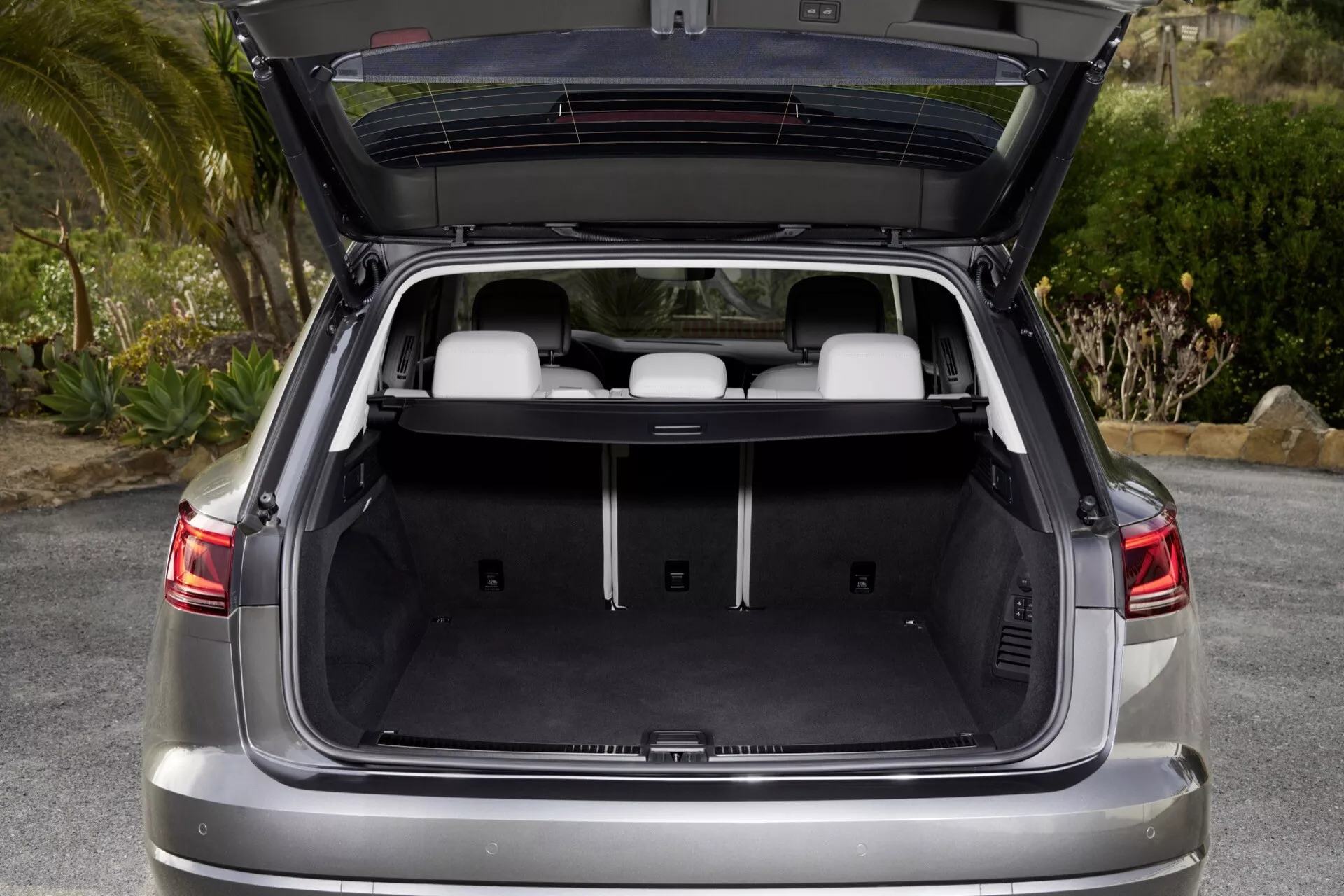 VW Touareg 2023 (III-facelift) montrant un espace de chargement arrière spacieux et propre avec hayon ouvert, reflétant le confort et la praticité, aux côtés d'éléments modernes tels que feux arrière réfléchissants et capteurs de stationnement indicatifs de la technologie d'assistance au stationnement