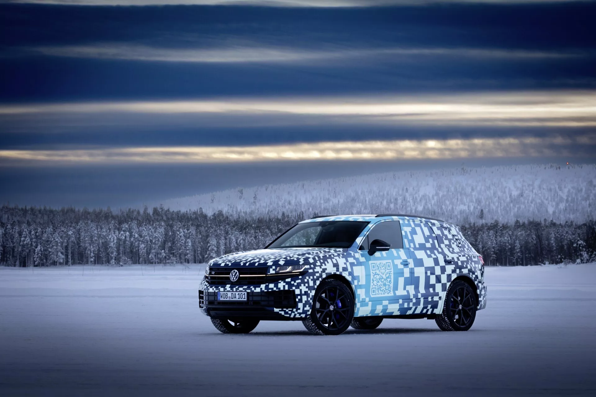 Vue de profil latéral du Volkswagen Touareg III facelift 2023 sur terrain enneigé avec un camouflage mettant en avant la longueur du véhicule, son design aérodynamique et système d'éclairage avancé