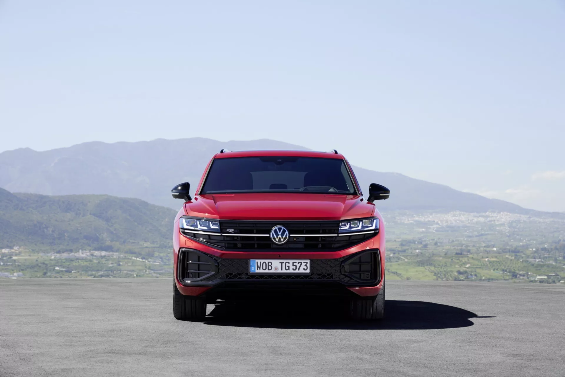 Vue de face d'un Volkswagen Touareg rouge 2023 (facelift III) montrant la grille intégrée et les blocs optiques LED, soulignant la dominance et les caractéristiques technologiques modernes du véhicule