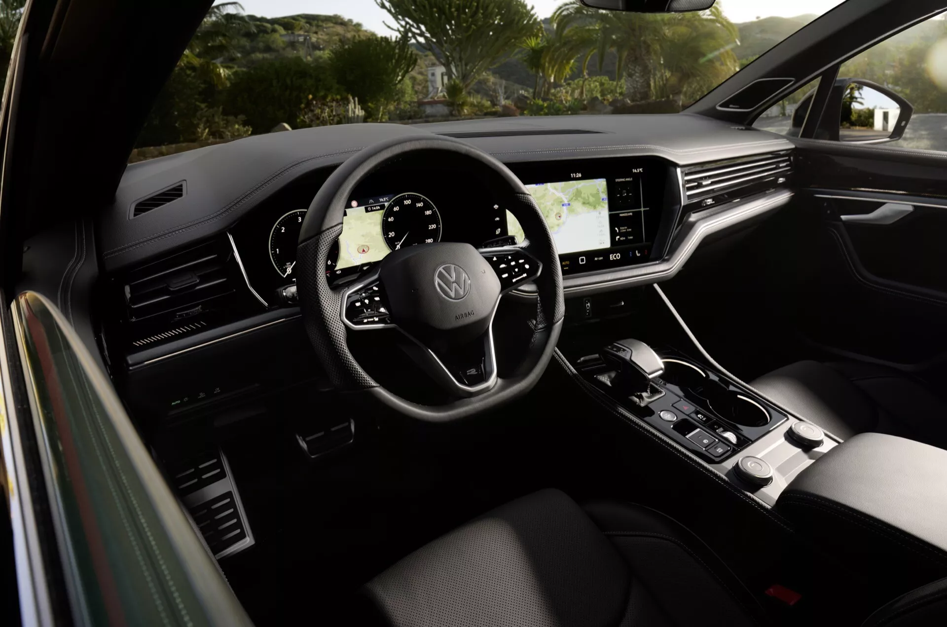 Intérieur du Volkswagen Touareg 2023 présentant un volant à trois branches avec logo de la marque, tableau de bord totalement numérique, grand écran tactile d'infodivertissement et levier de vitesse élégant, mettant en évidence le design moderne de la voiture et les fonctionnalités technologiques avancées
