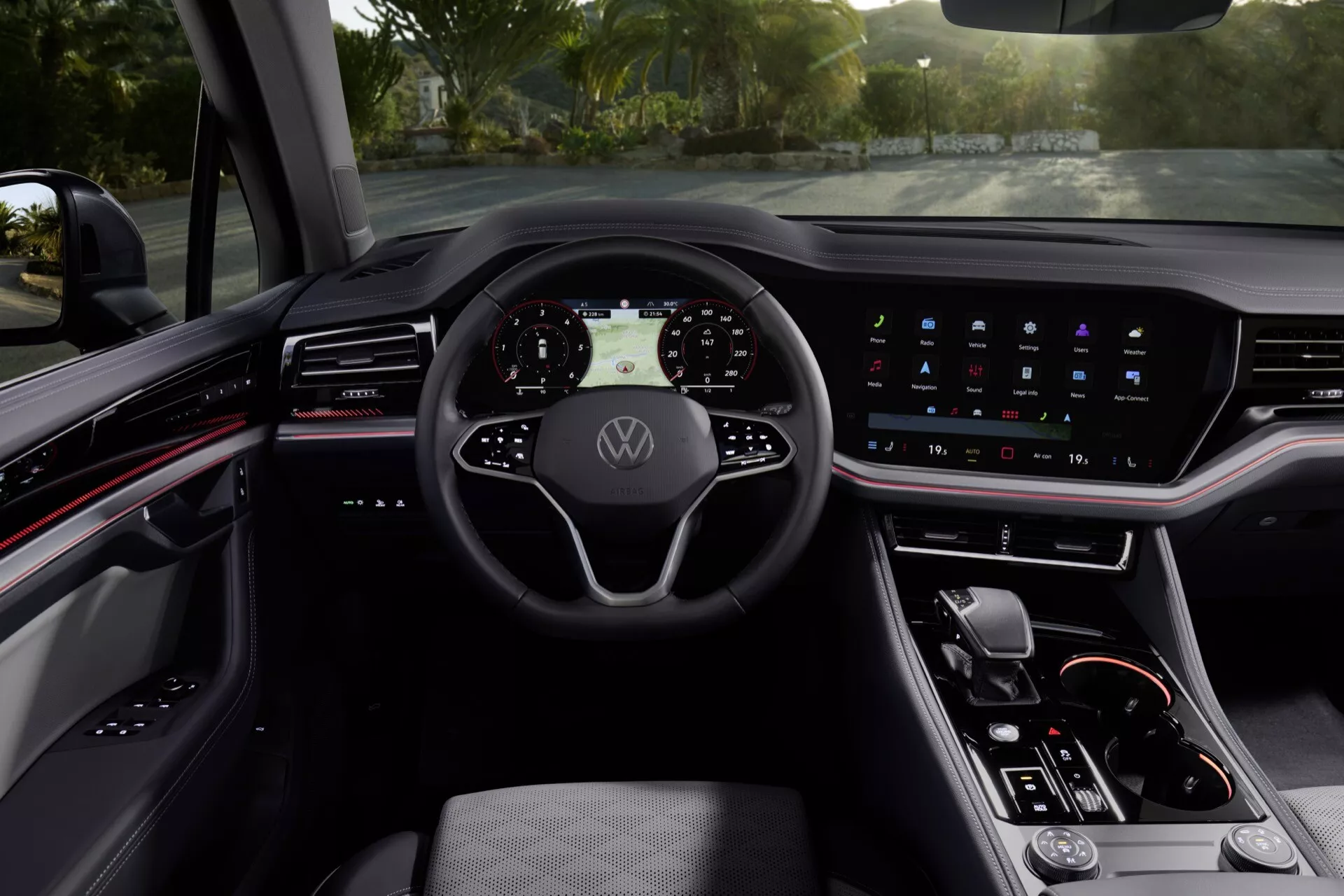 Intérieur du Volkswagen Touareg (III-Facelift) 2023 présentant un tableau de bord numérique, un volant multifonction avec emblème Volkswagen, un écran tactile infotainment intégré, des commandes minimalistes sur la console centrale et un schéma de couleurs sombres sophistiqué avec éclairage d'ambiance