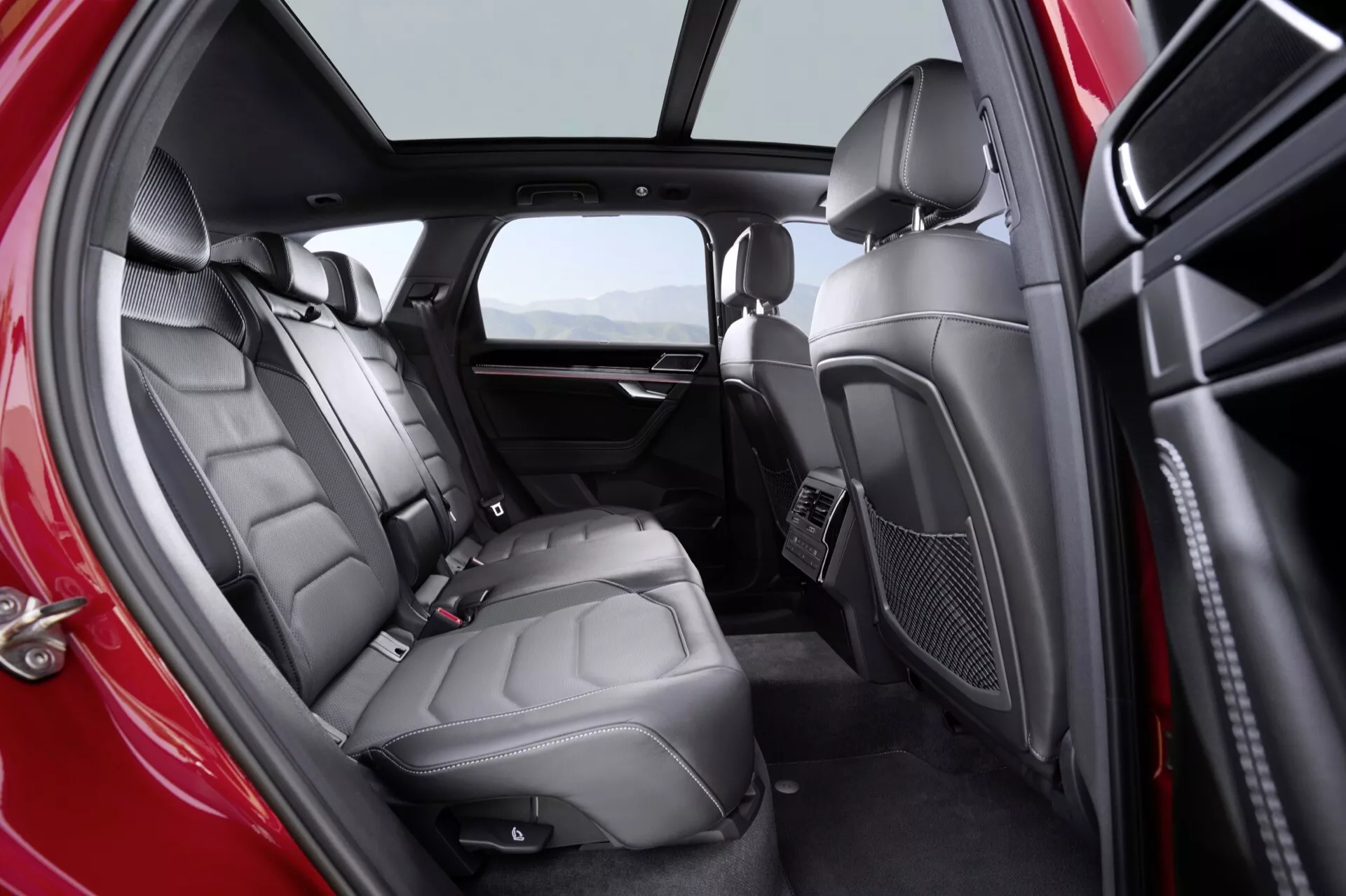 Photo de l'intérieur du Volkswagen Touareg (III Facelift) 2023 montrant le compartiment passager arrière luxueux avec sièges en cuir premium, système de divertissement intégré, toit panoramique et signaux de design sophistiqués du point de vue du côté droit du spectateur