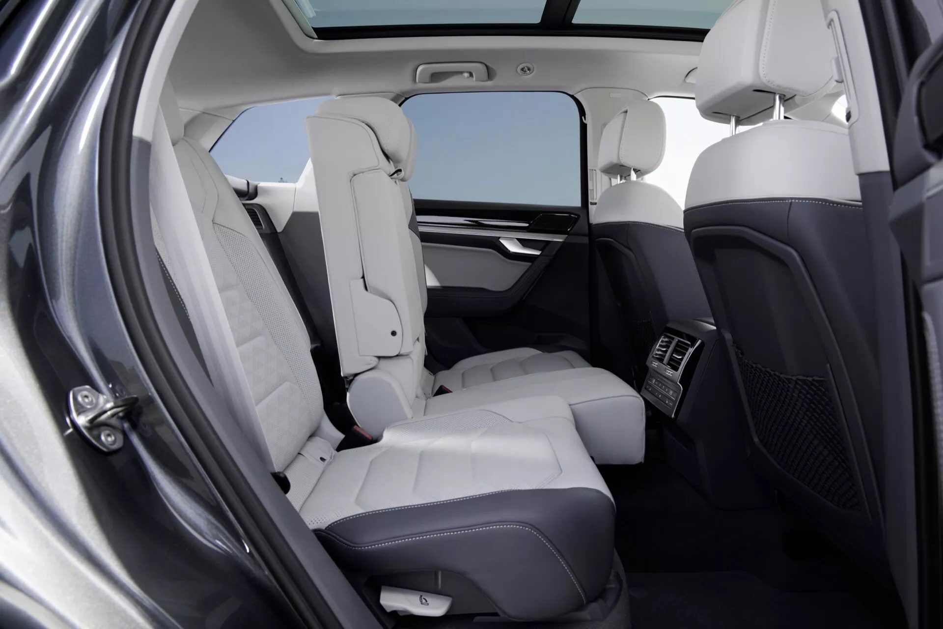 Intérieur du Volkswagen Touareg 2023 (III-Facelift) montrant le compartiment arrière pour passagers de luxe avec sièges en cuir clair, toit panoramique et espace généreux pour les jambes
