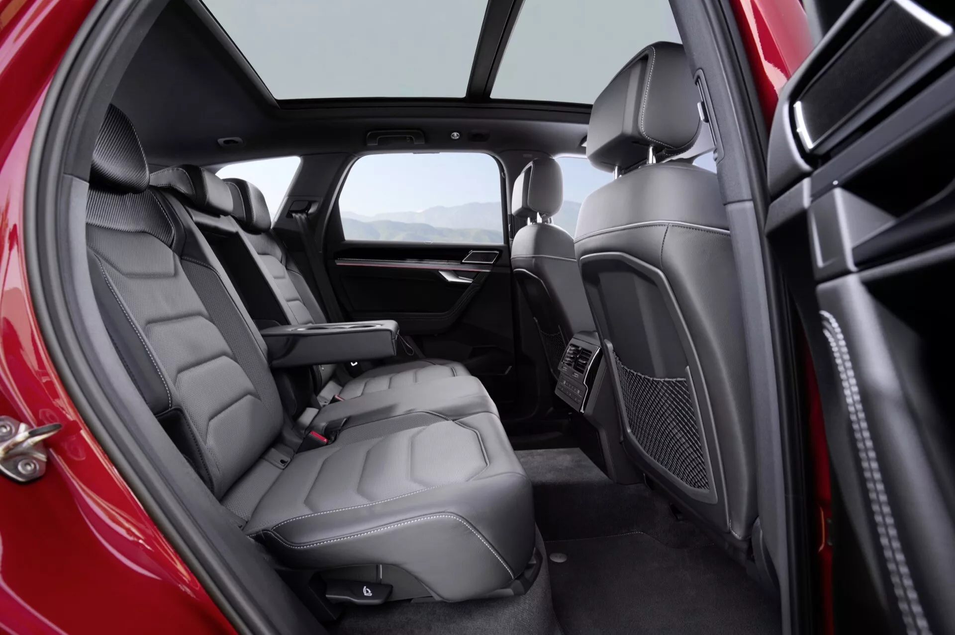 Vue intérieure du VW Touareg III face-lift 2023 mettant en évidence les sièges arrière en cuir luxueux et les fonctionnalités avancées de confort pour les passagers, avec éclairage naturel et schéma de couleurs en deux tons