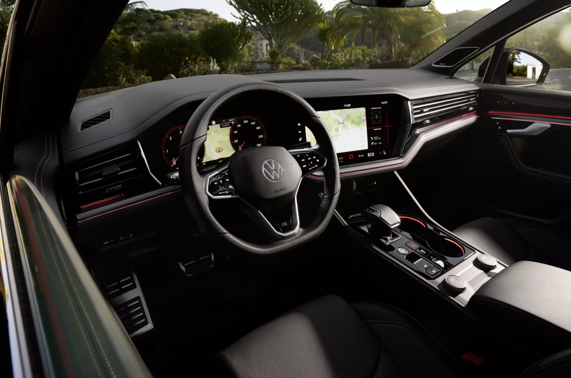 Vue intérieure du Volkswagen Touareg 2023 depuis le siège passager arrière montrant le volant avec logo, le tableau de bord numérique et la console centrale tactile
