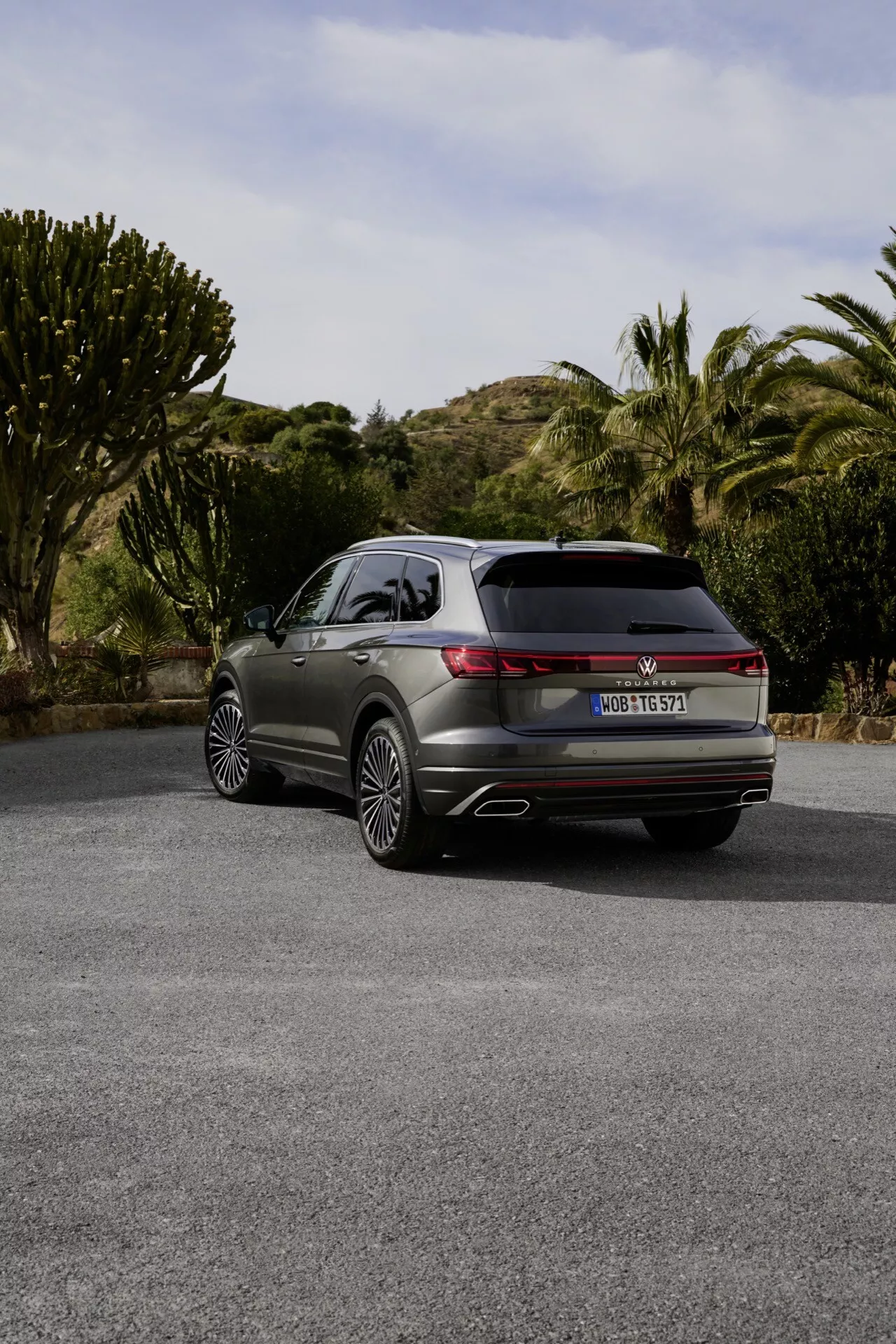 VW Touareg 2023 (III-facelift) vu d'un angle arrière de trois quarts mettant en avant des feux arrière LED, des échappements doubles et des jantes en alliage premium sur une route semi-rurale